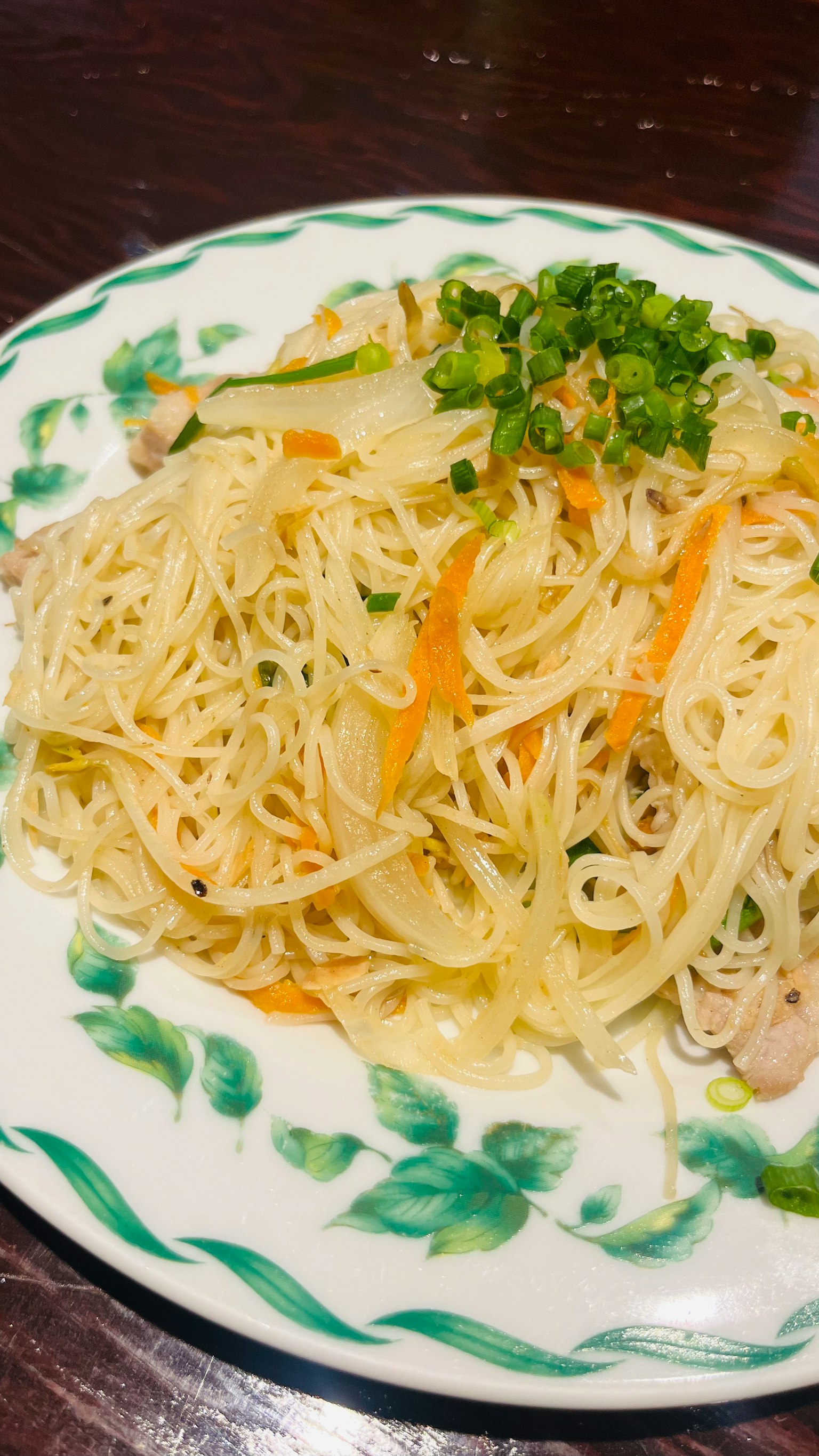Piatto di noodles fini guarnito con verdure e cipolle verdi