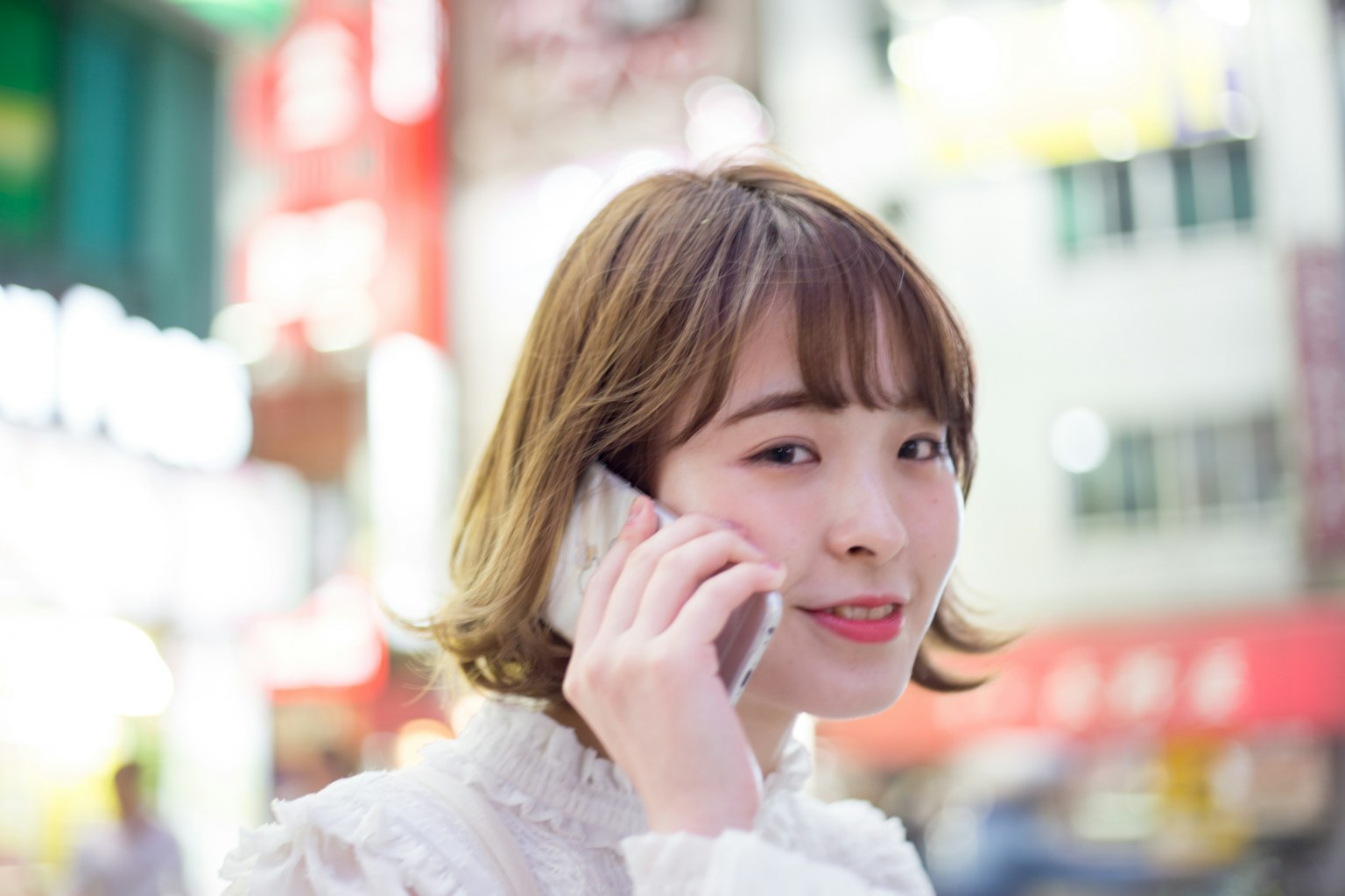 Smiling woman on the phone with neon signs in the background