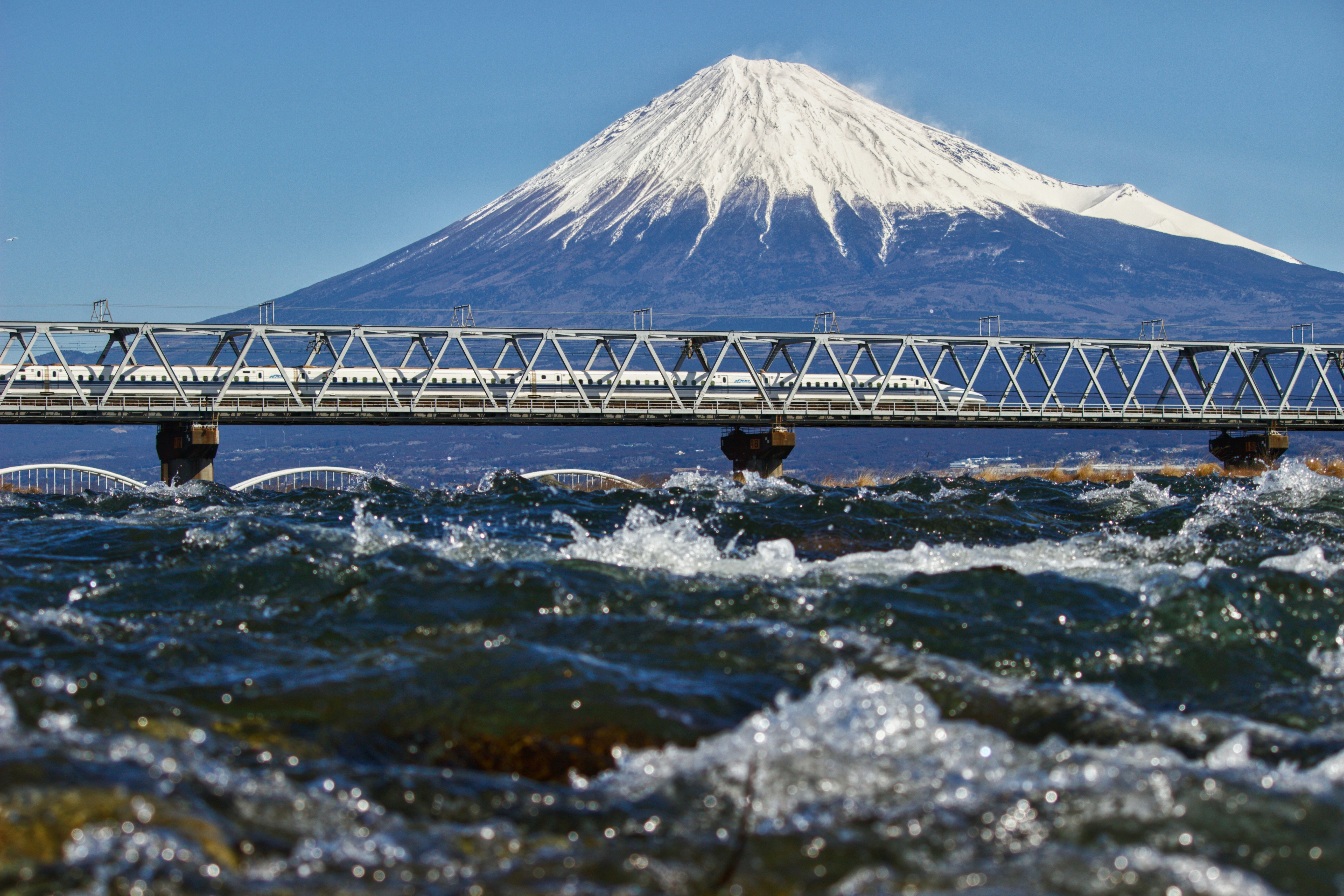 雪化粧した富士山と富士川を走る新幹線の眺め