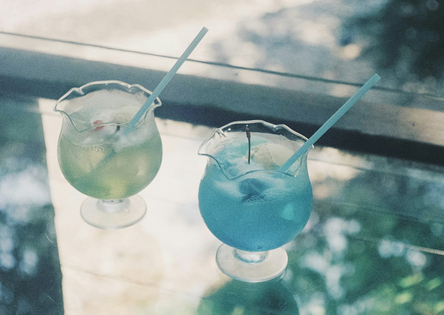 两个绿色和蓝色的鸡尾酒在玻璃桌上
