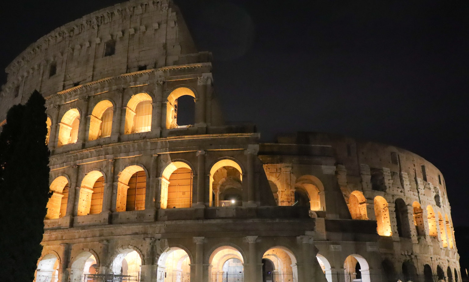 Archi illuminati del Colosseo di notte che mostrano la sua antica struttura in pietra