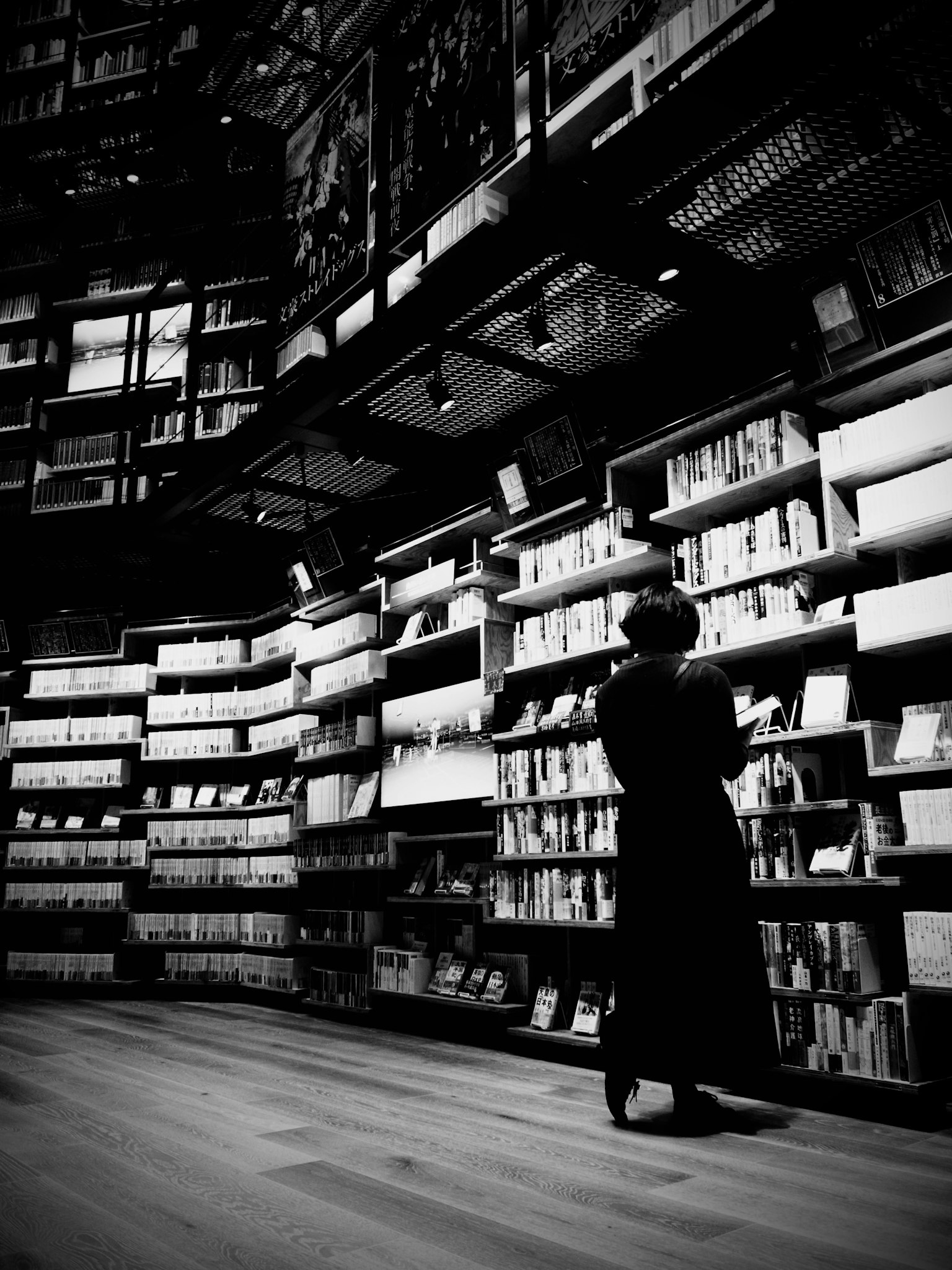 Silhouette d'une femme cherchant des livres dans une bibliothèque sombre