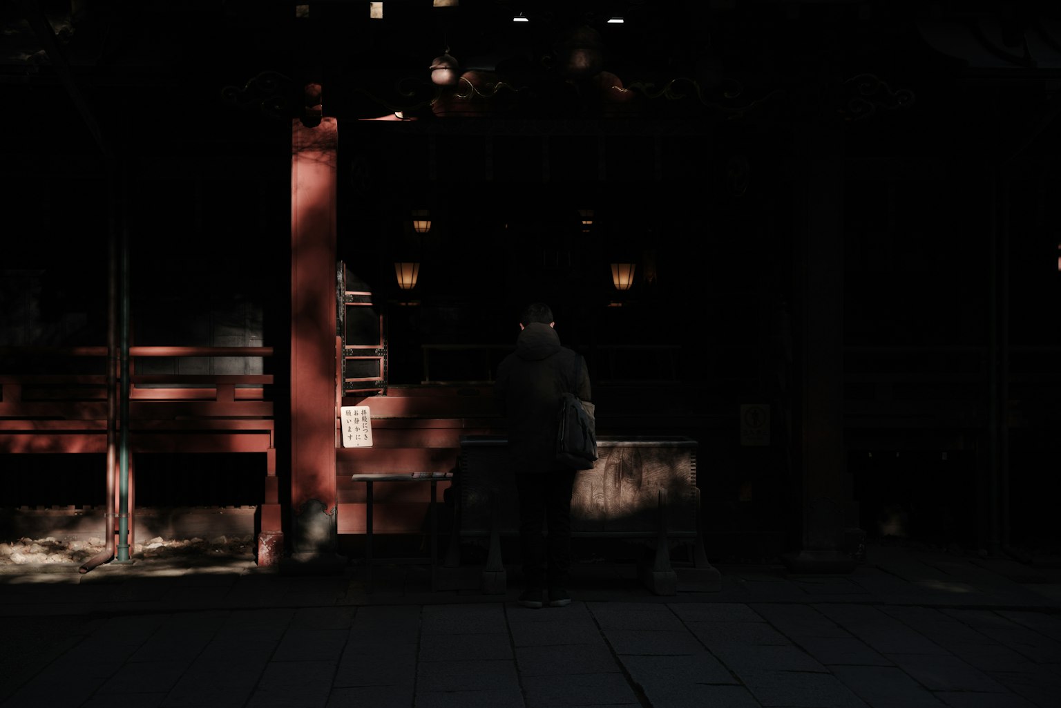 在黑暗背景前站立的人影與紅色建築的燈光