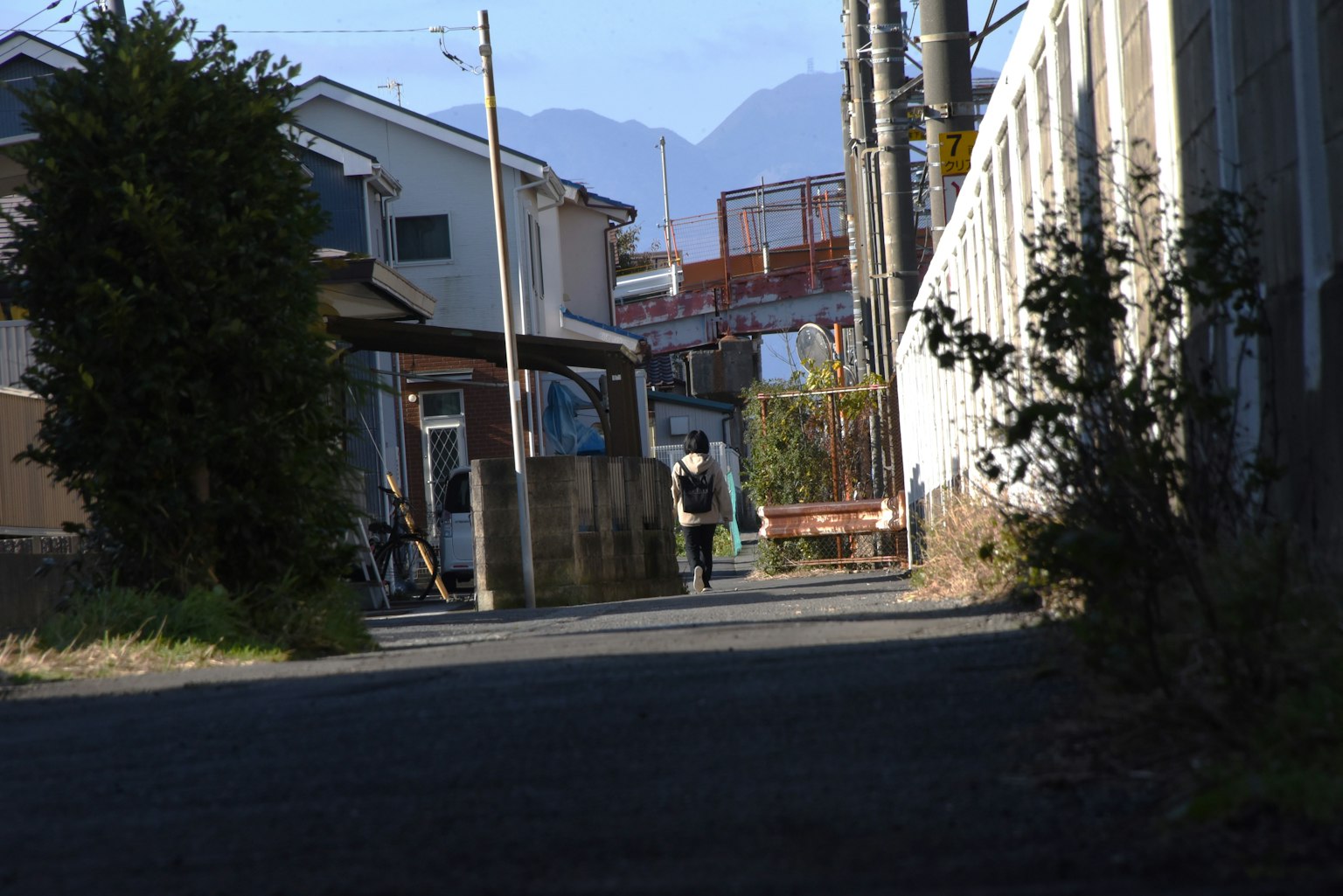 一個人在狹窄的街道上走，旁邊是住宅建築