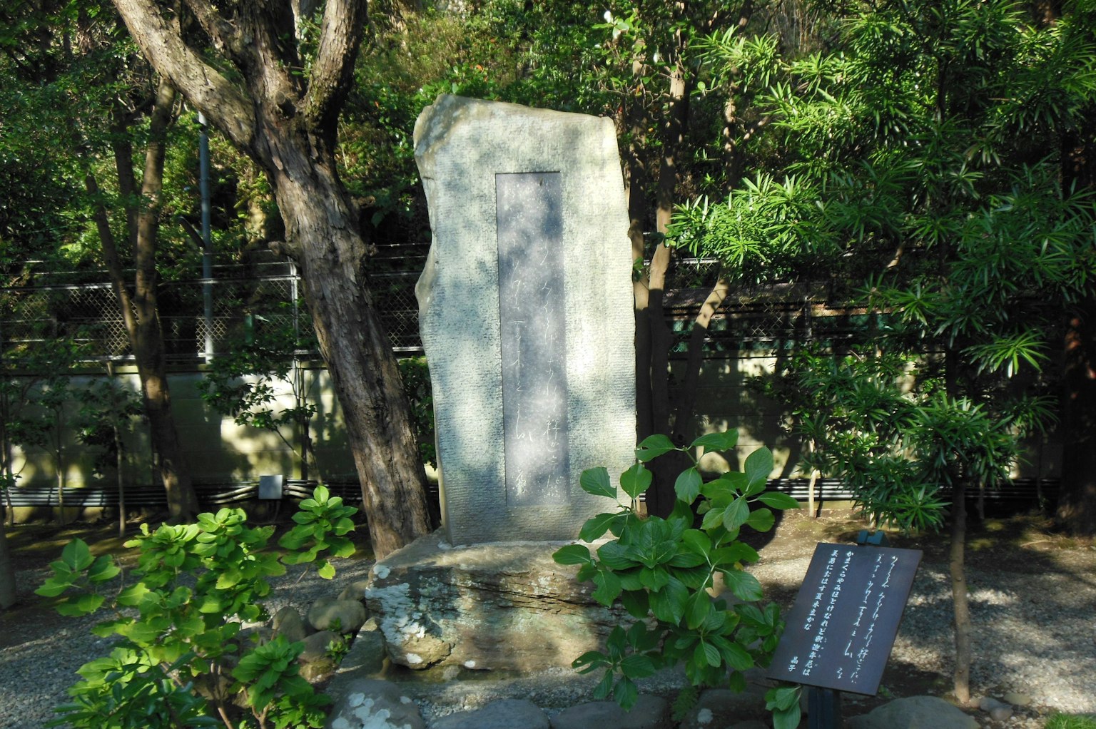 A stone monument surrounded by greenery with an information plaque