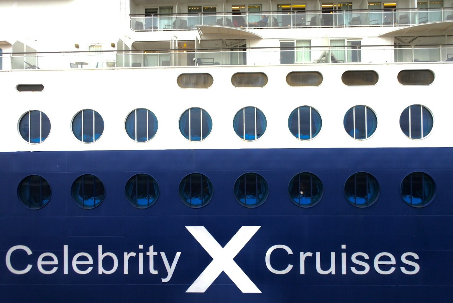 มุมมองด้านข้างของเรือ Celebrity X Cruises ที่มีหน้าต่างวงกลมและโลโก้