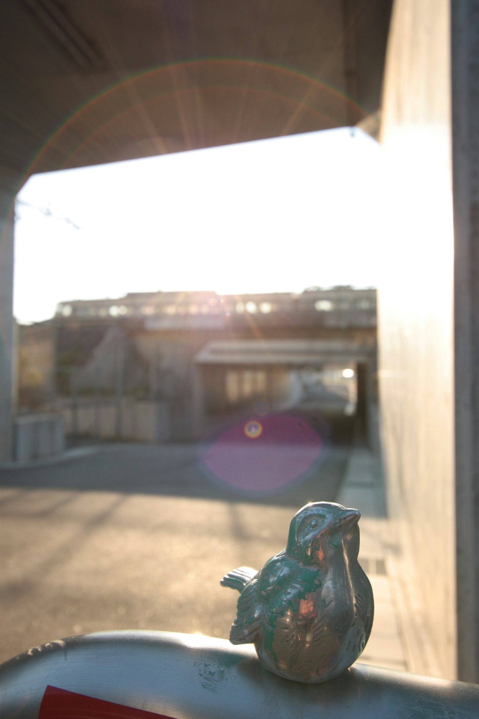 Türkisfarbene Vogelstatue vor einem sonnigen Tunnel