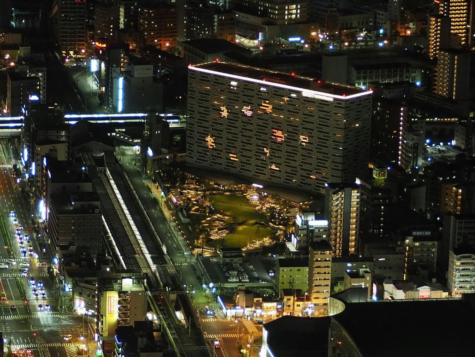 Paisaje urbano nocturno con rascacielos y carreteras incluyendo un área verde de parque