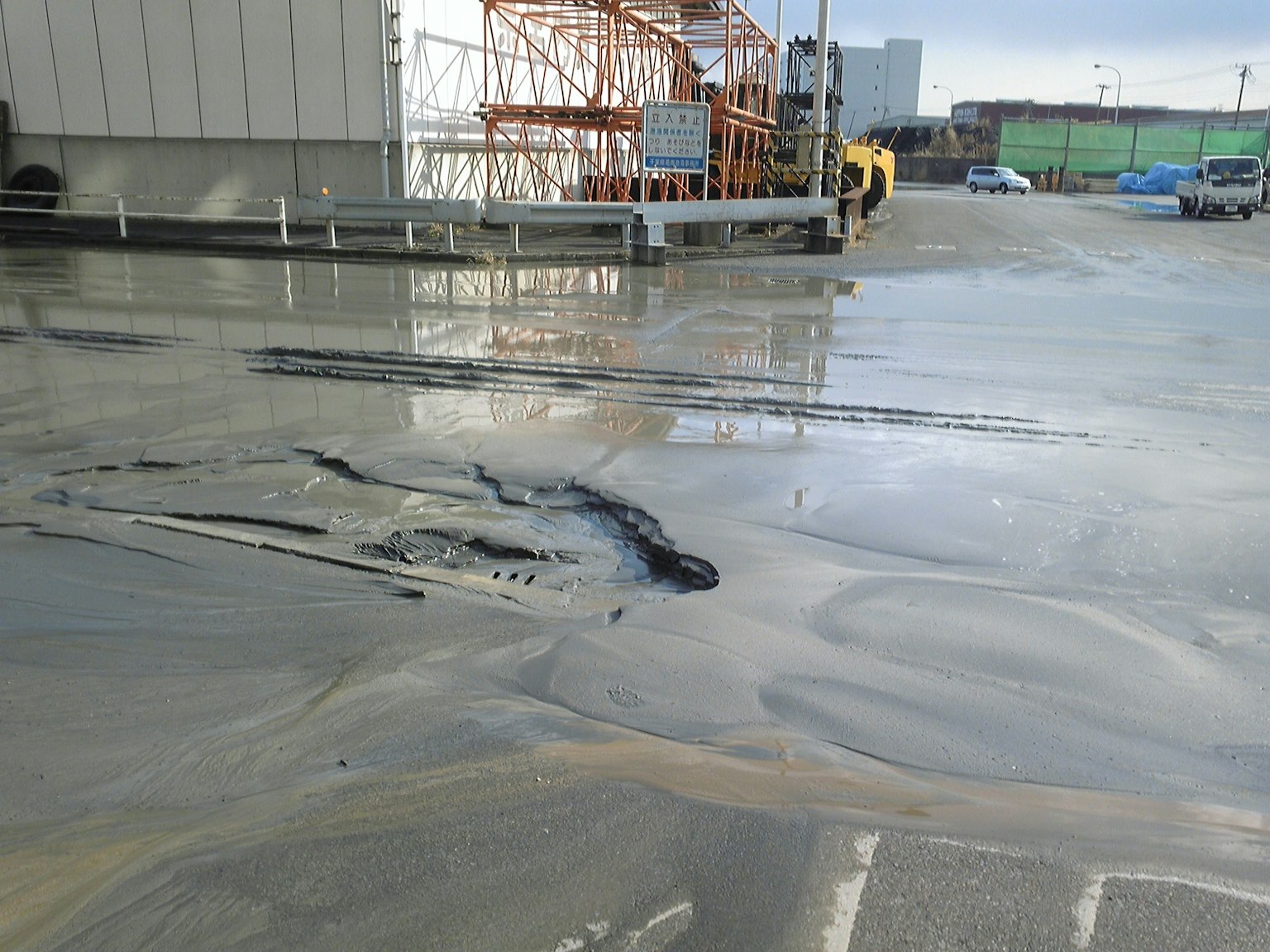 Baustelle mit nasser Betonoberfläche und umliegenden Strukturen