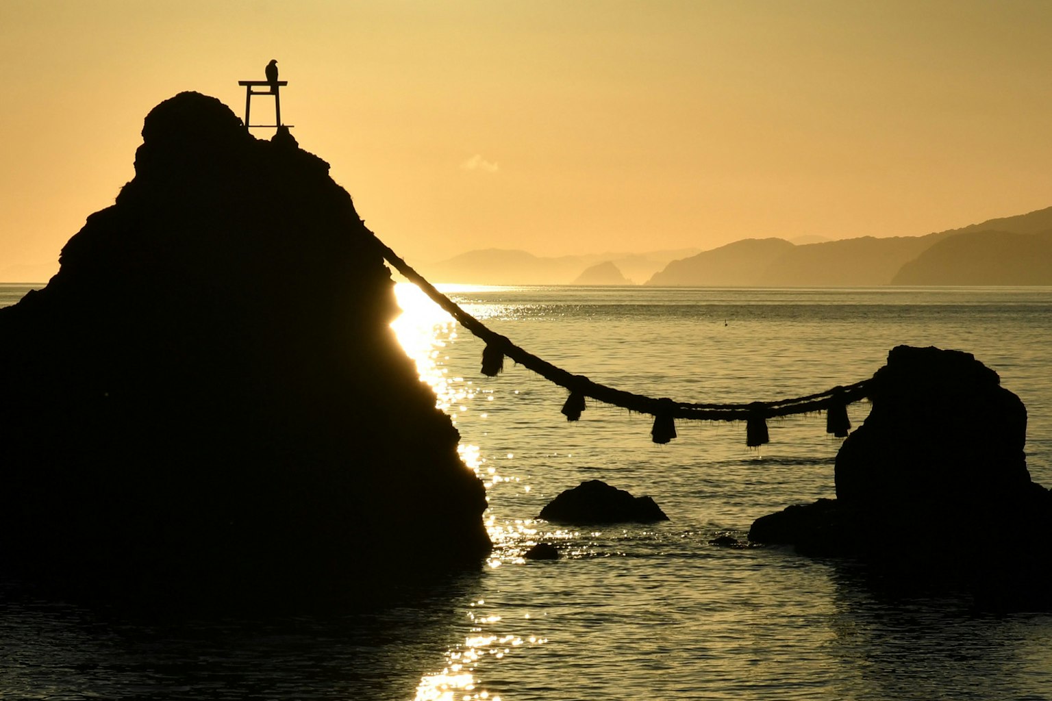 Silhouette di rocce e di un ponte di corda al tramonto