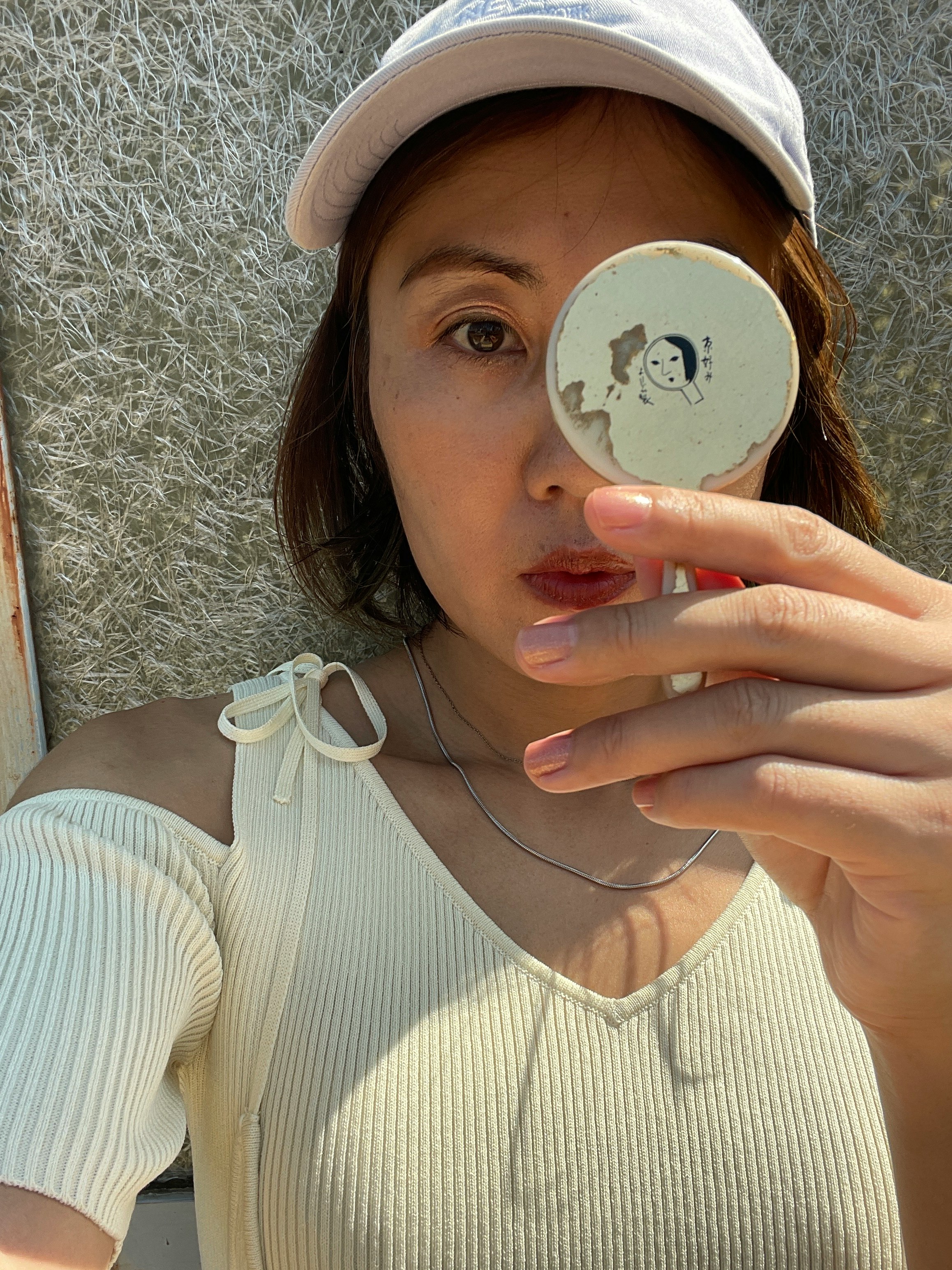 拿着“看不见的镜子”道具贴在脸颊的女性