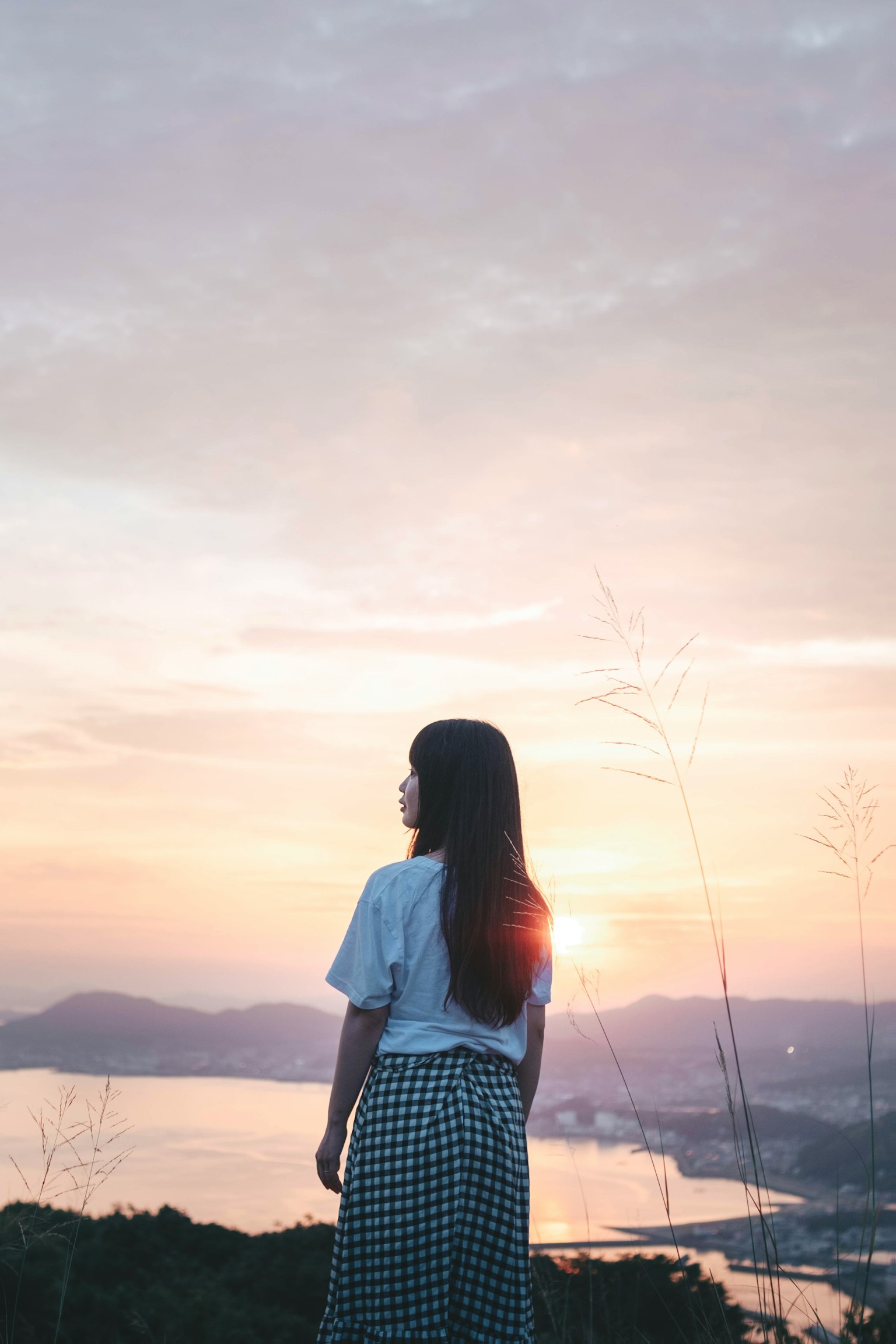 一个女人站在山顶，背景是日落