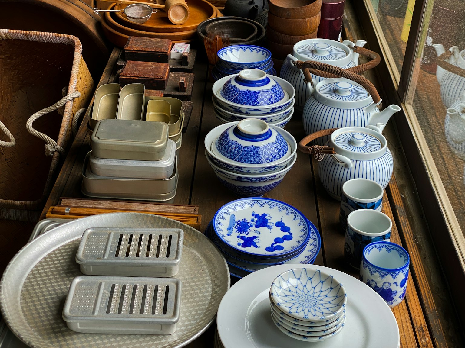 Tavolo pieno di ceramiche blu e bianche insieme a vassoi e ciotole in metallo