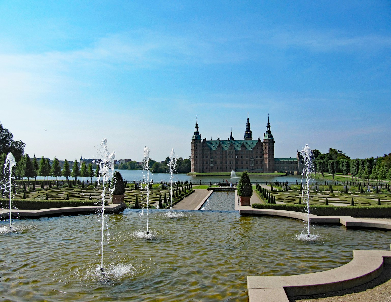 Jardines con fuentes y vista de un castillo grandioso