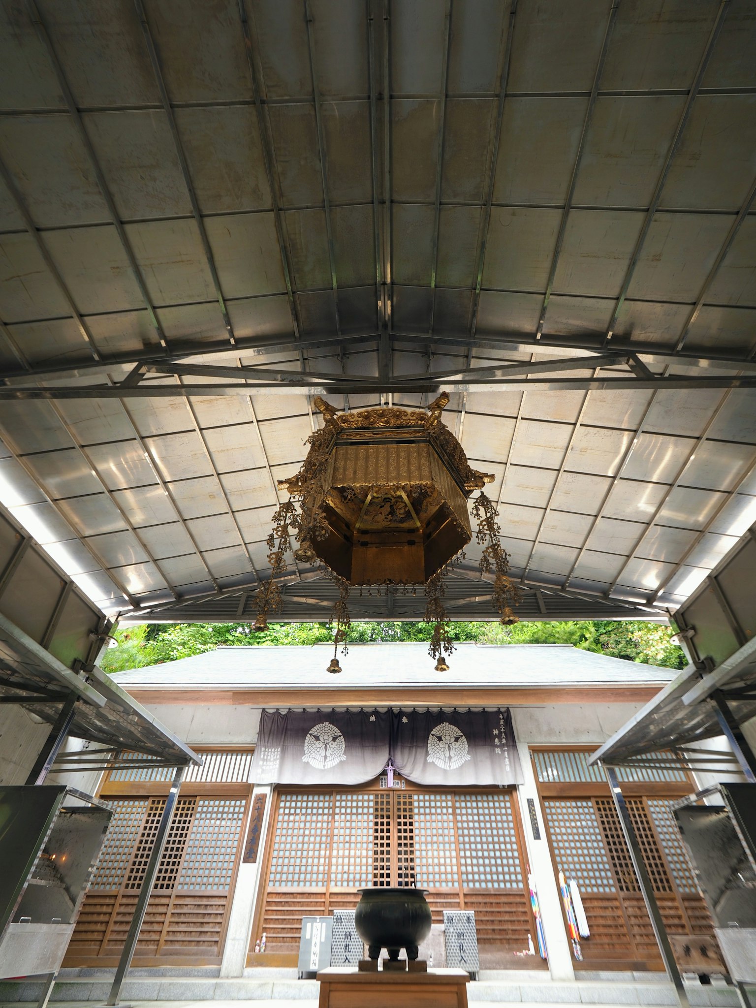 Interior sebuah kuil dengan atap lampu dekoratif tergantung di tengah rak kayu di sekeliling