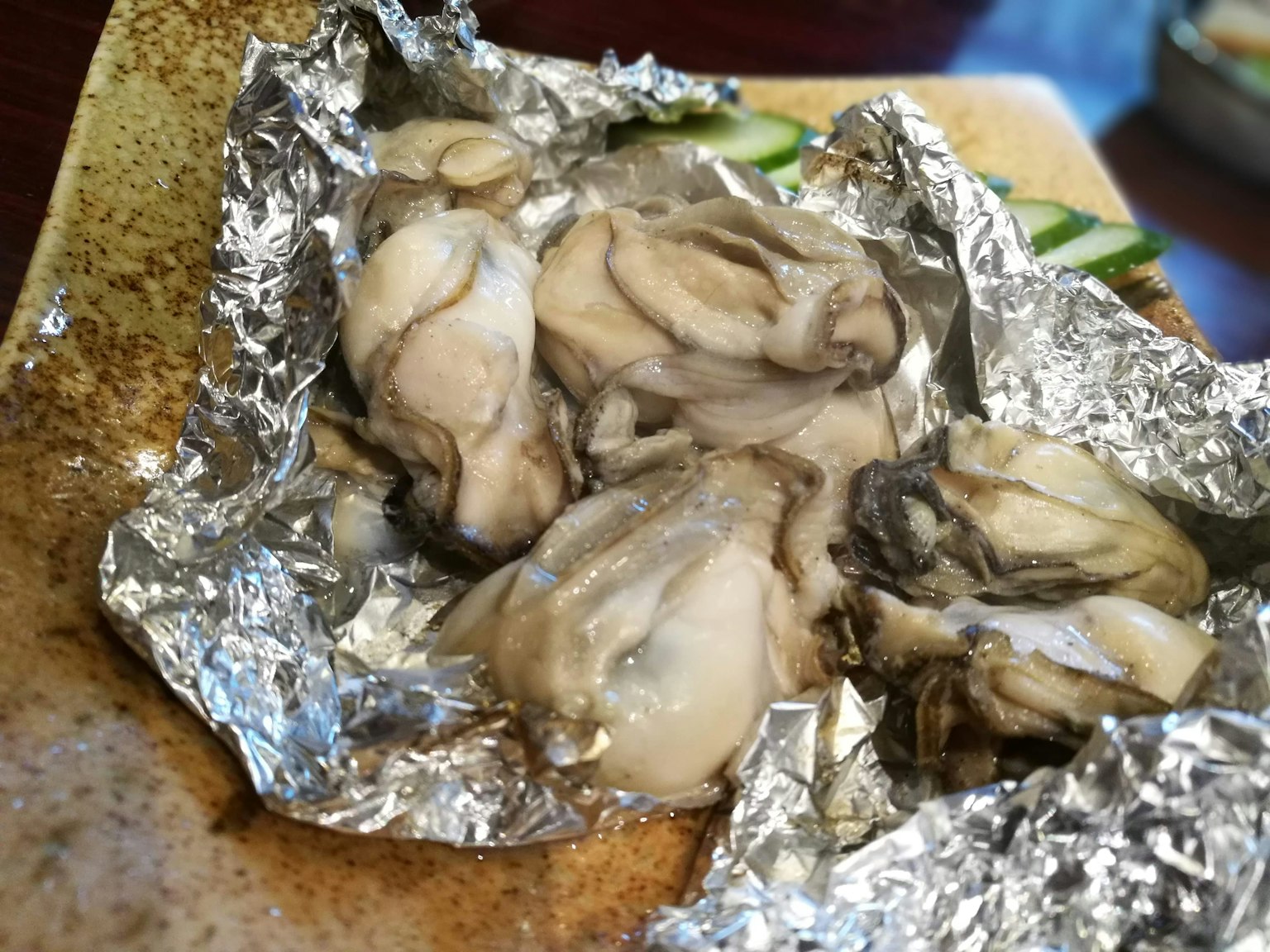 Fresh oysters served on a plate wrapped in silver foil