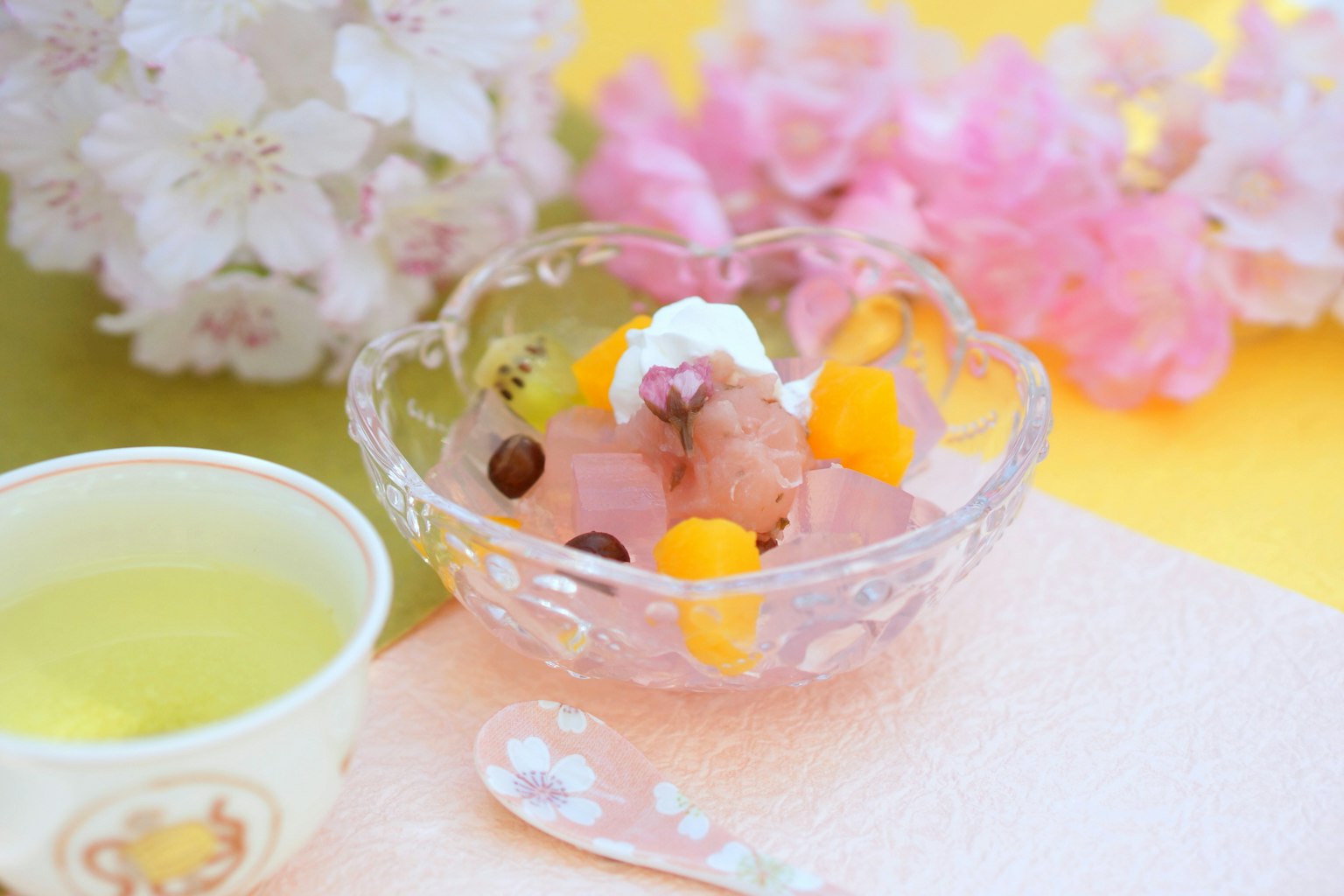Un delicado postre de frutas servido en un tazón de vidrio con flores de cerezo al fondo