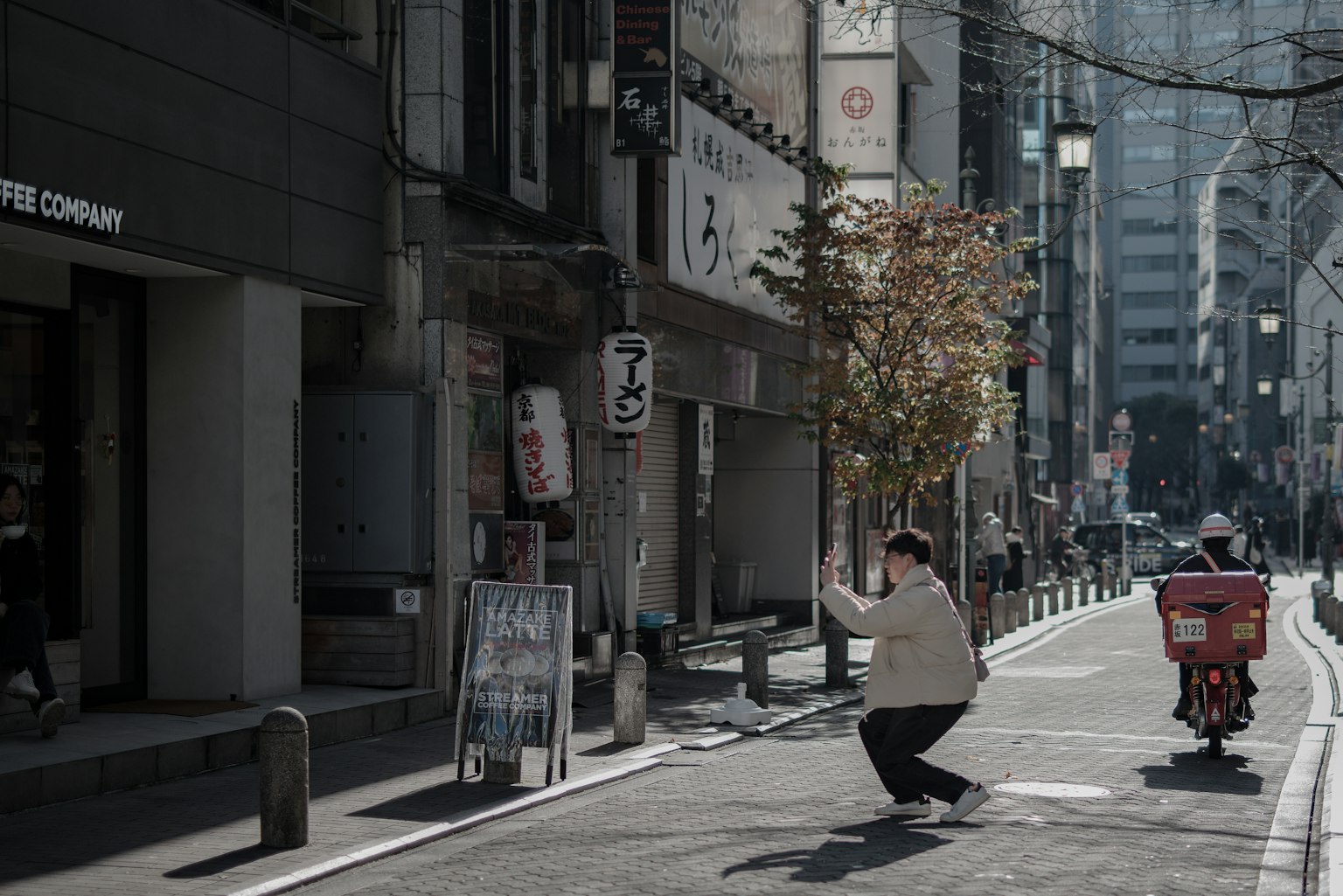 Une personne en mouvement dans une rue de Tokyo avec une livraison à vélo à proximité