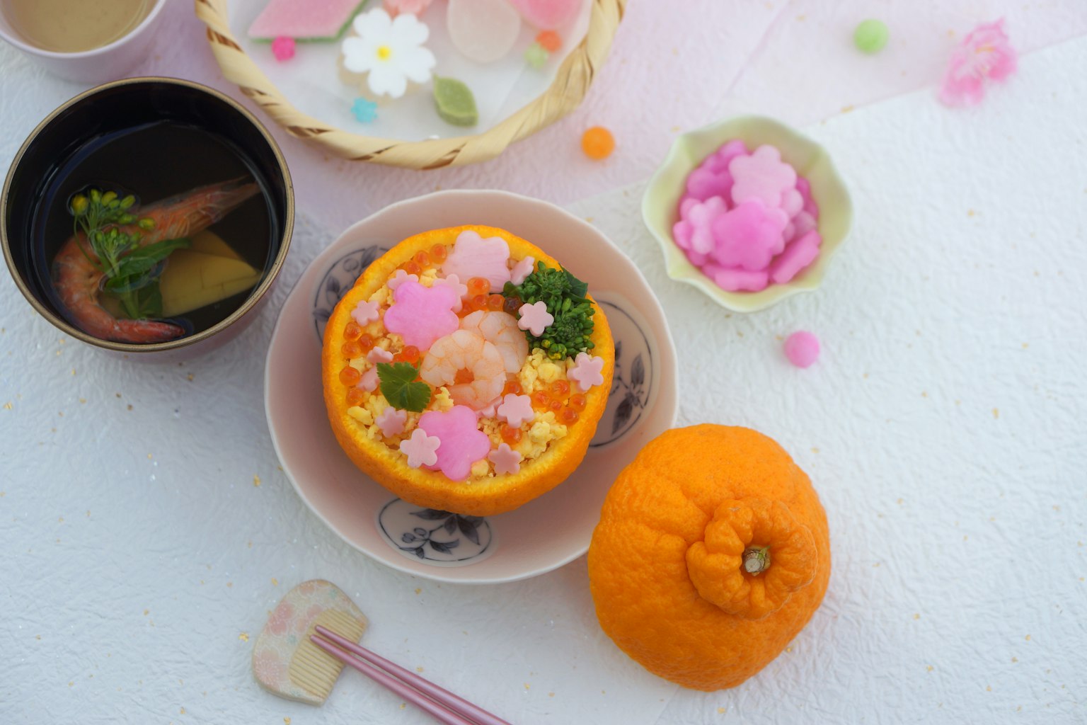 Buntes Sushi in einer orangefarbenen Schüssel mit blütenförmigen Toppings serviert