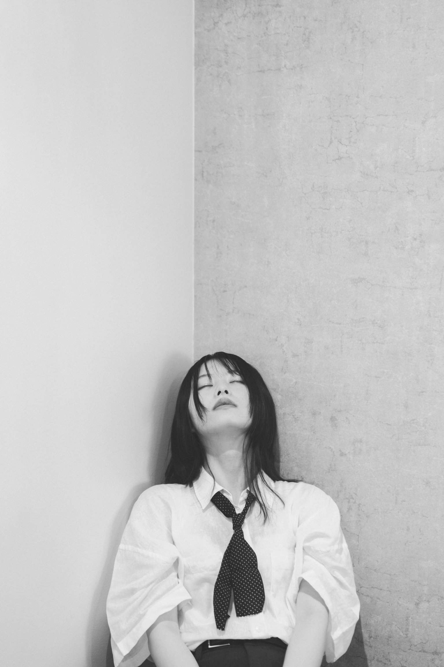 黑白图像中一名女性靠在墙角