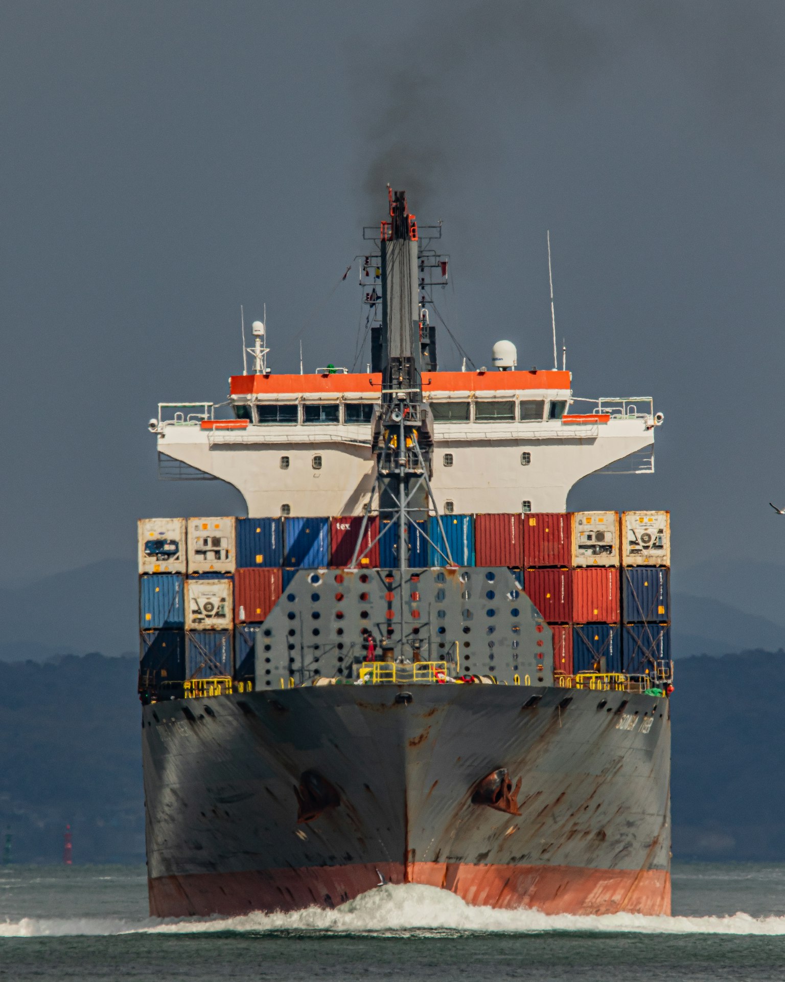 Buque portacontenedores avanzando emitiendo humo