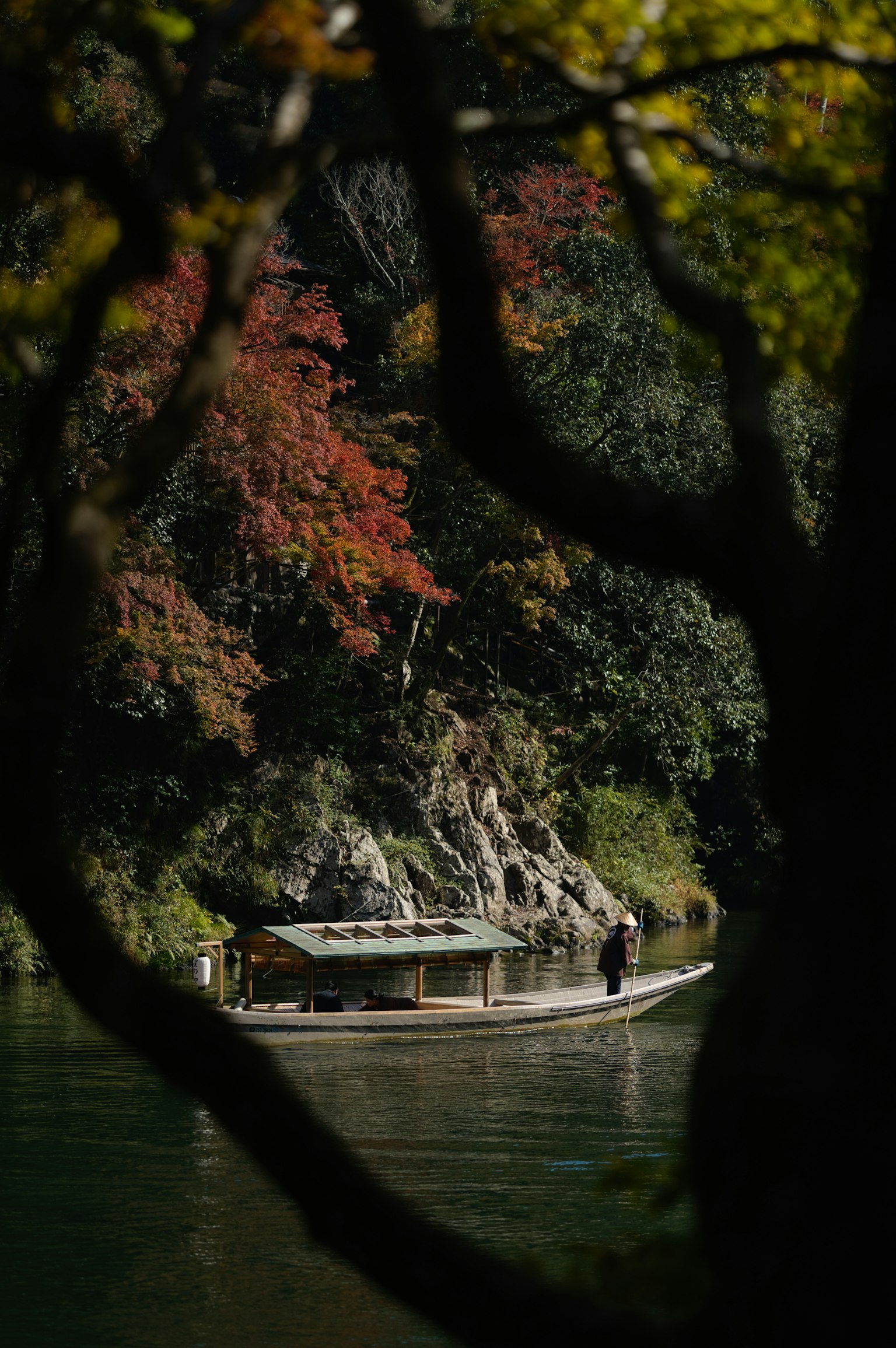 秋の紅葉に囲まれた川で舟に乗る人
