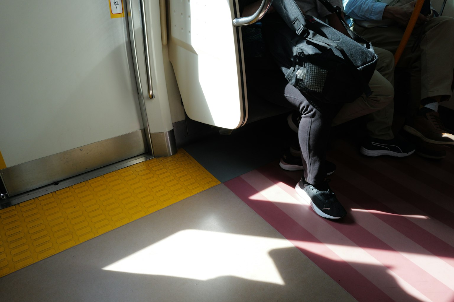 火車內部，地面上光影對比，顯示一人的腿部