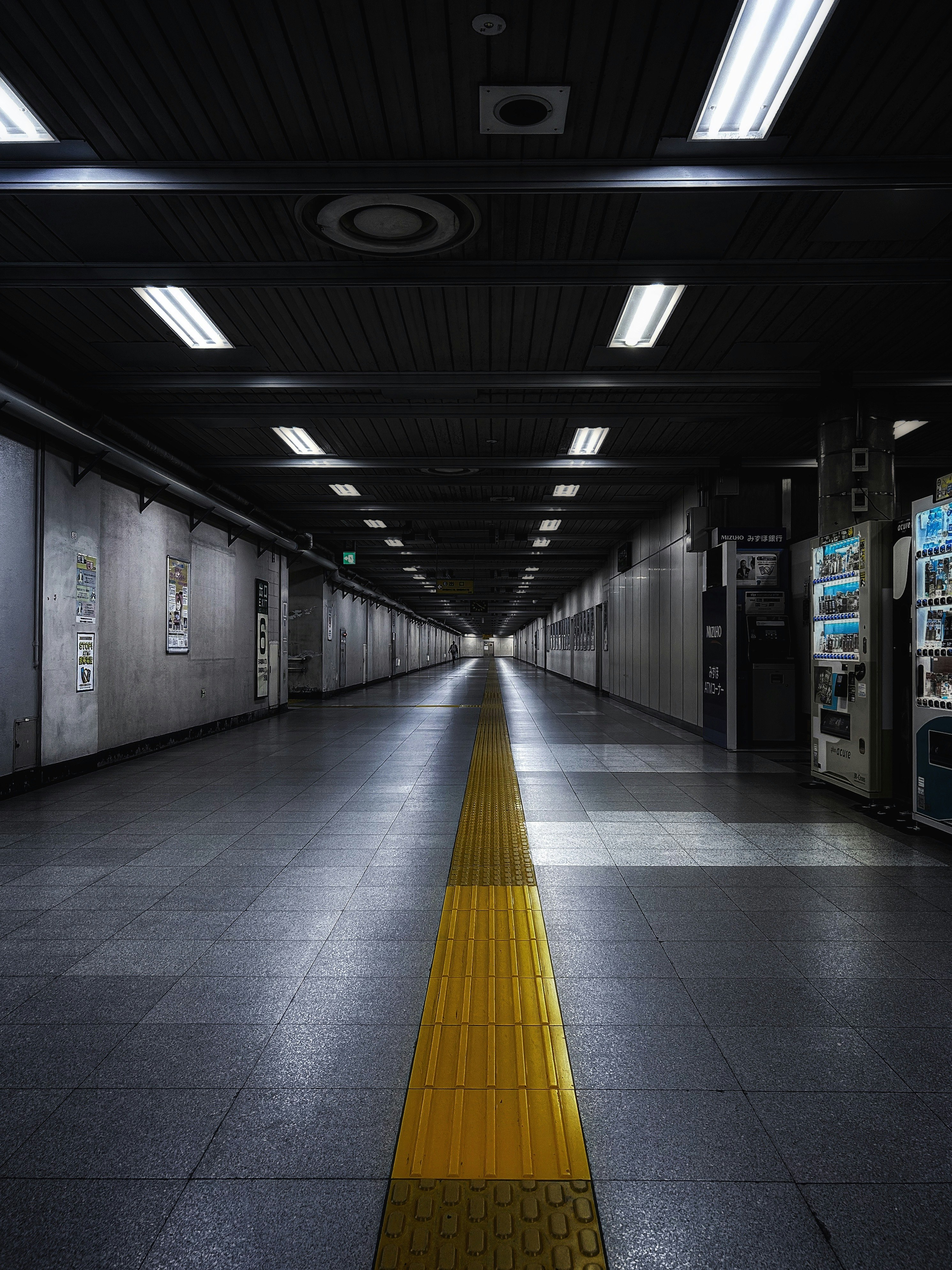 地下通路の長い廊下と黄色い誘導ブロックのある駅構内