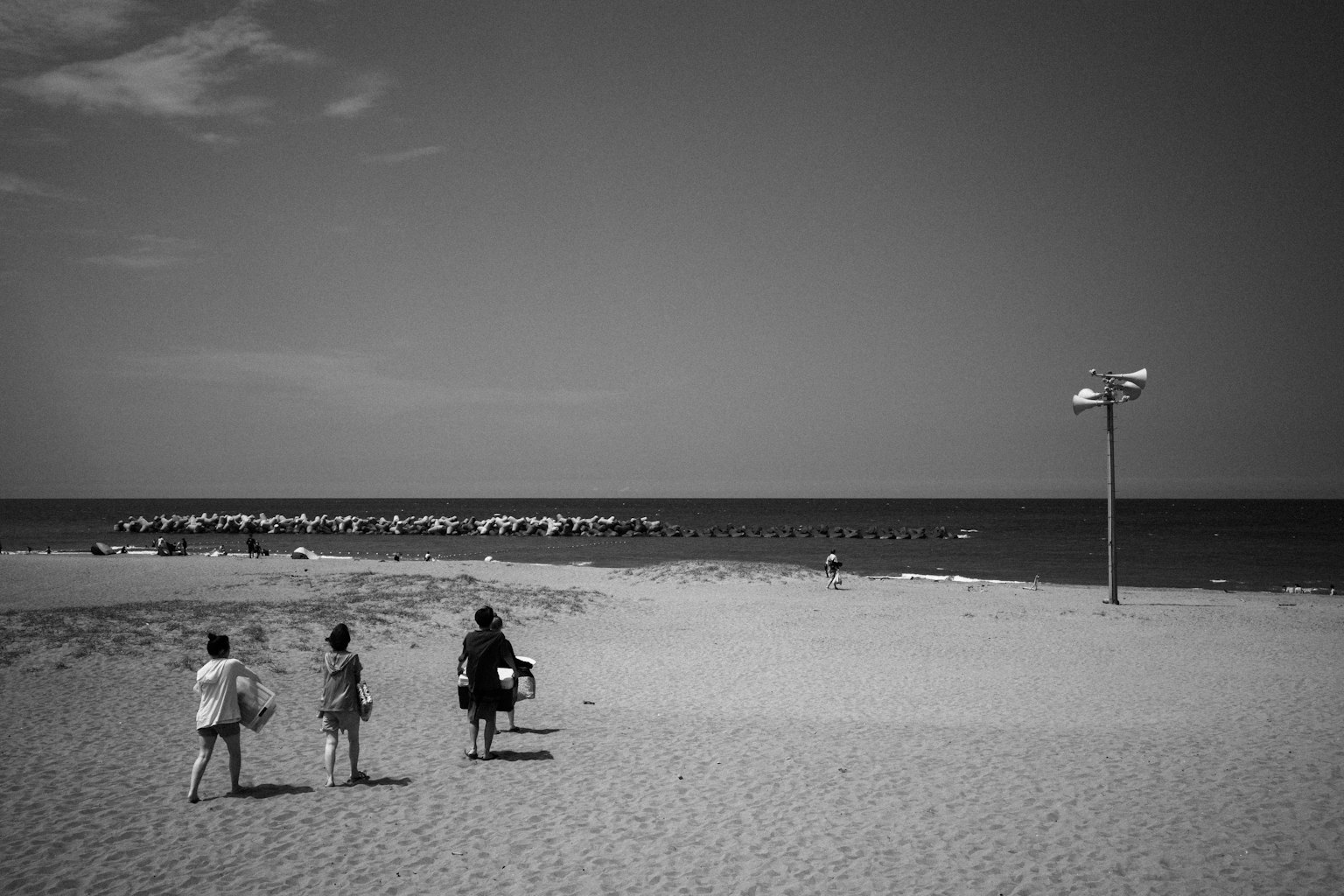 Tre bambini che camminano verso la spiaggia con un mare calmo sullo sfondo