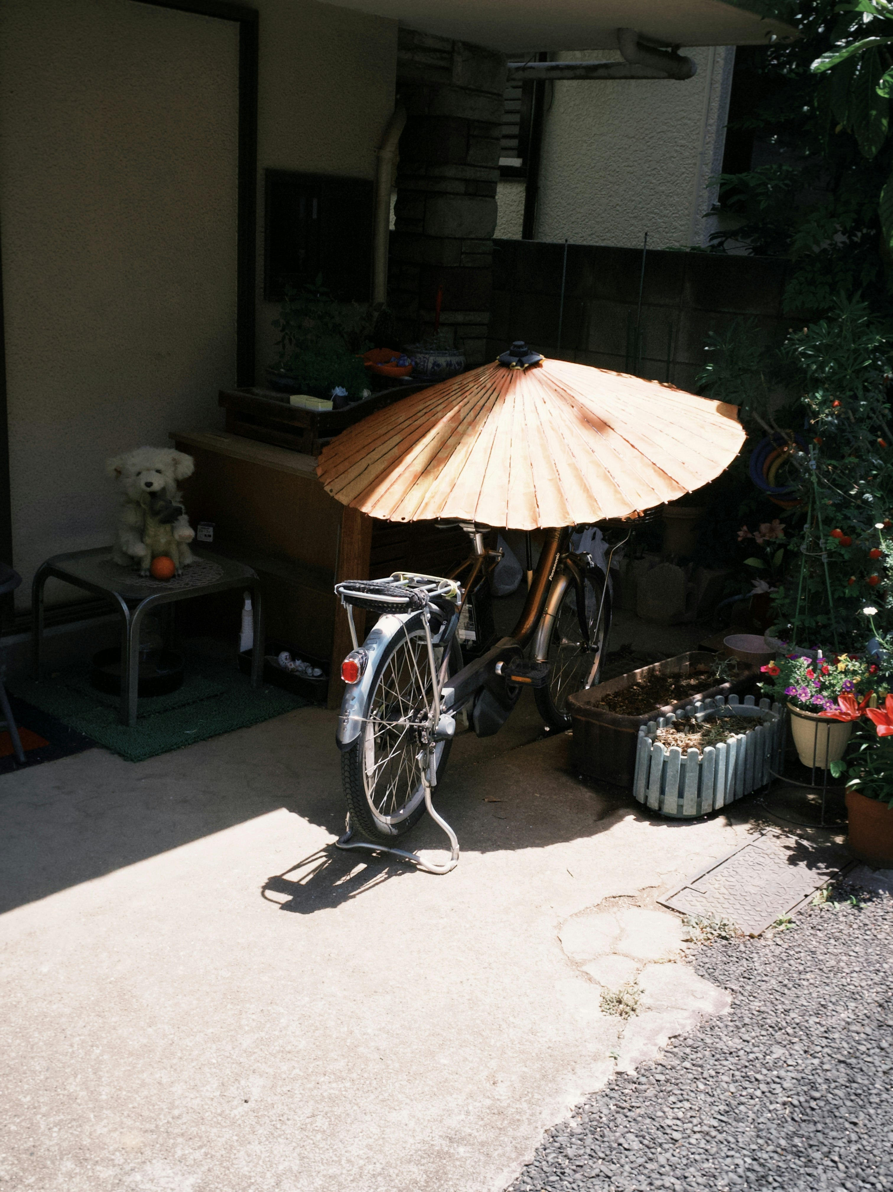 日差しの下で自転車と傘が置かれた中庭の小さな花の飾り
