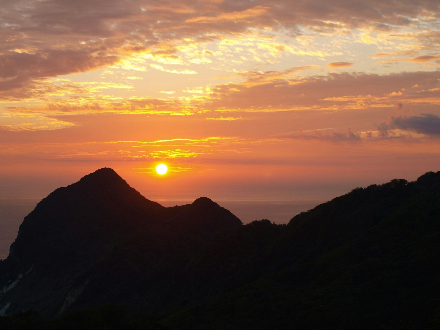 ทิวทัศน์ที่สวยงามพร้อมซิลลูเอทของภูเขาและพระอาทิตย์ตกที่สดใส