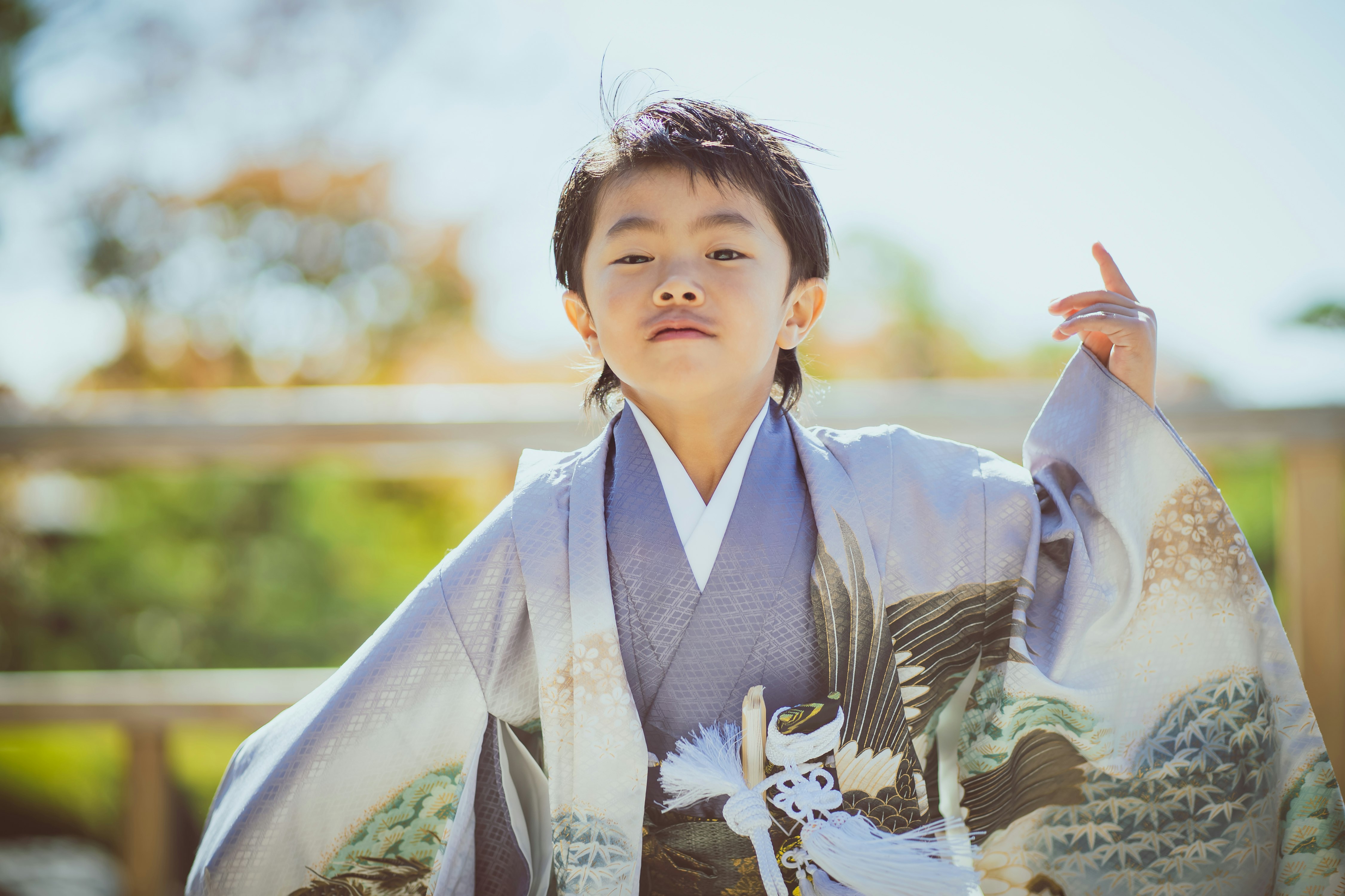 七五三の着物姿の男の子が手にお守り袋を持つ屋外の晴れた一枚