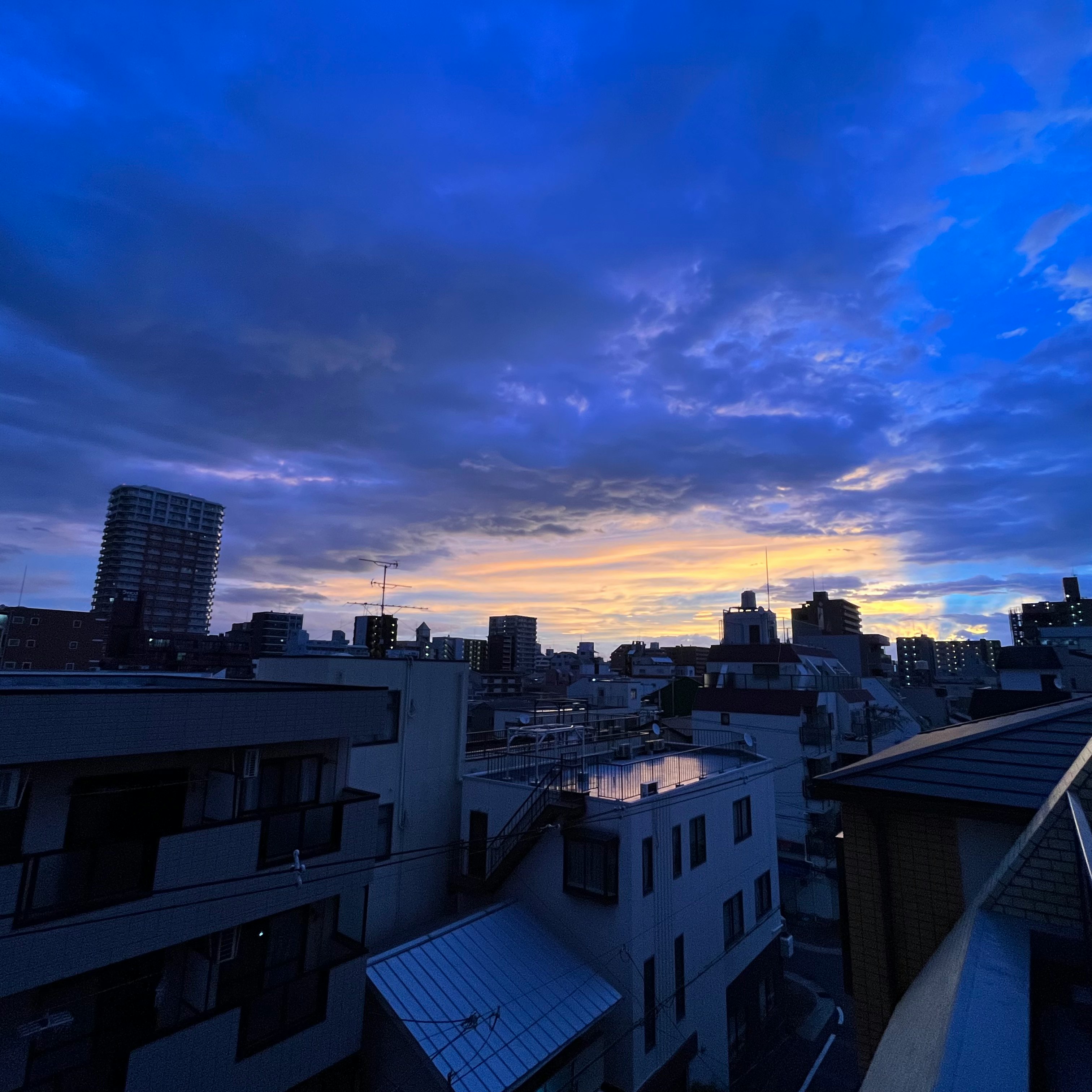 夕焼けの空と住宅街の屋根が広がる都市風景