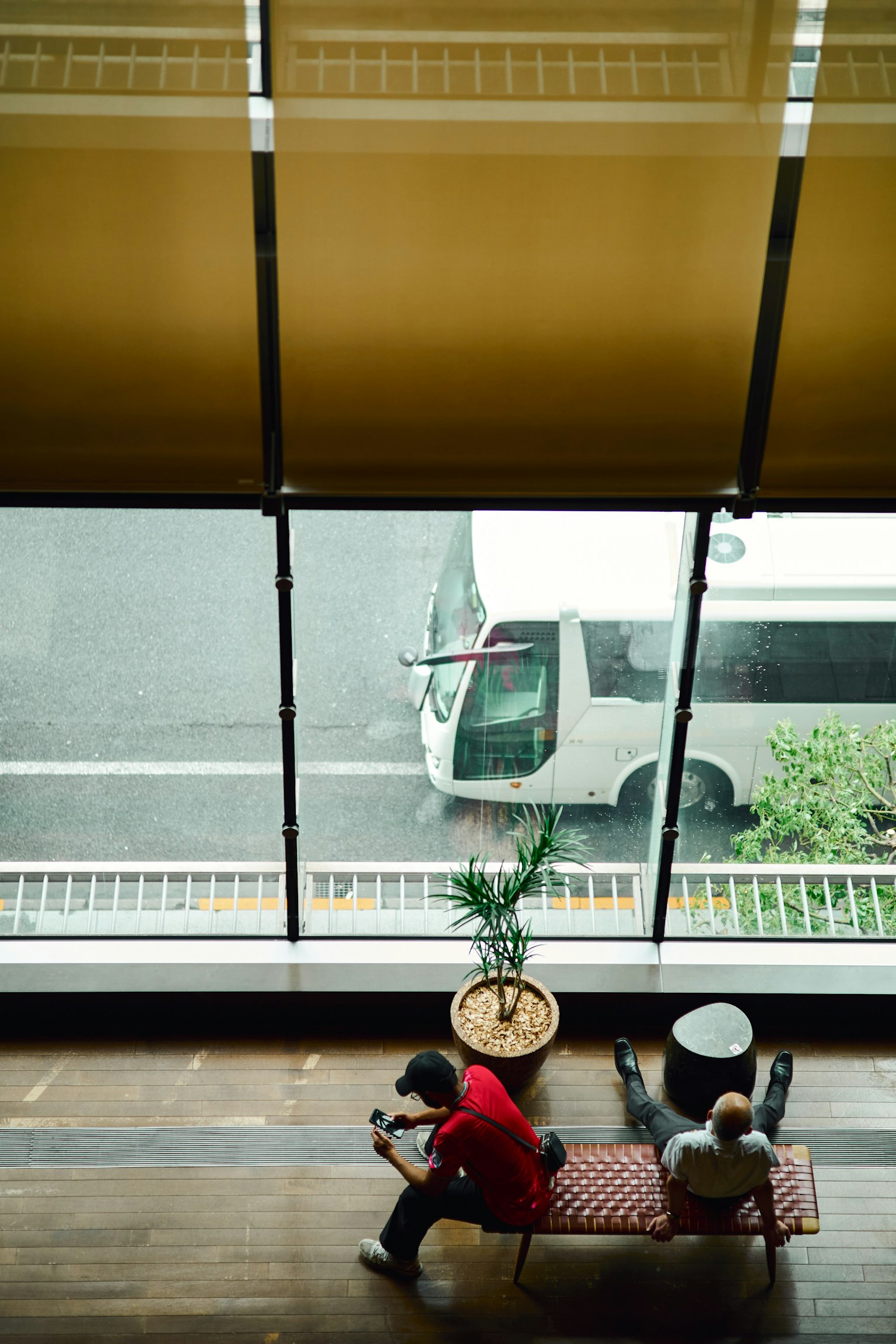 Interior view with two people sitting and a bus visible outside the window