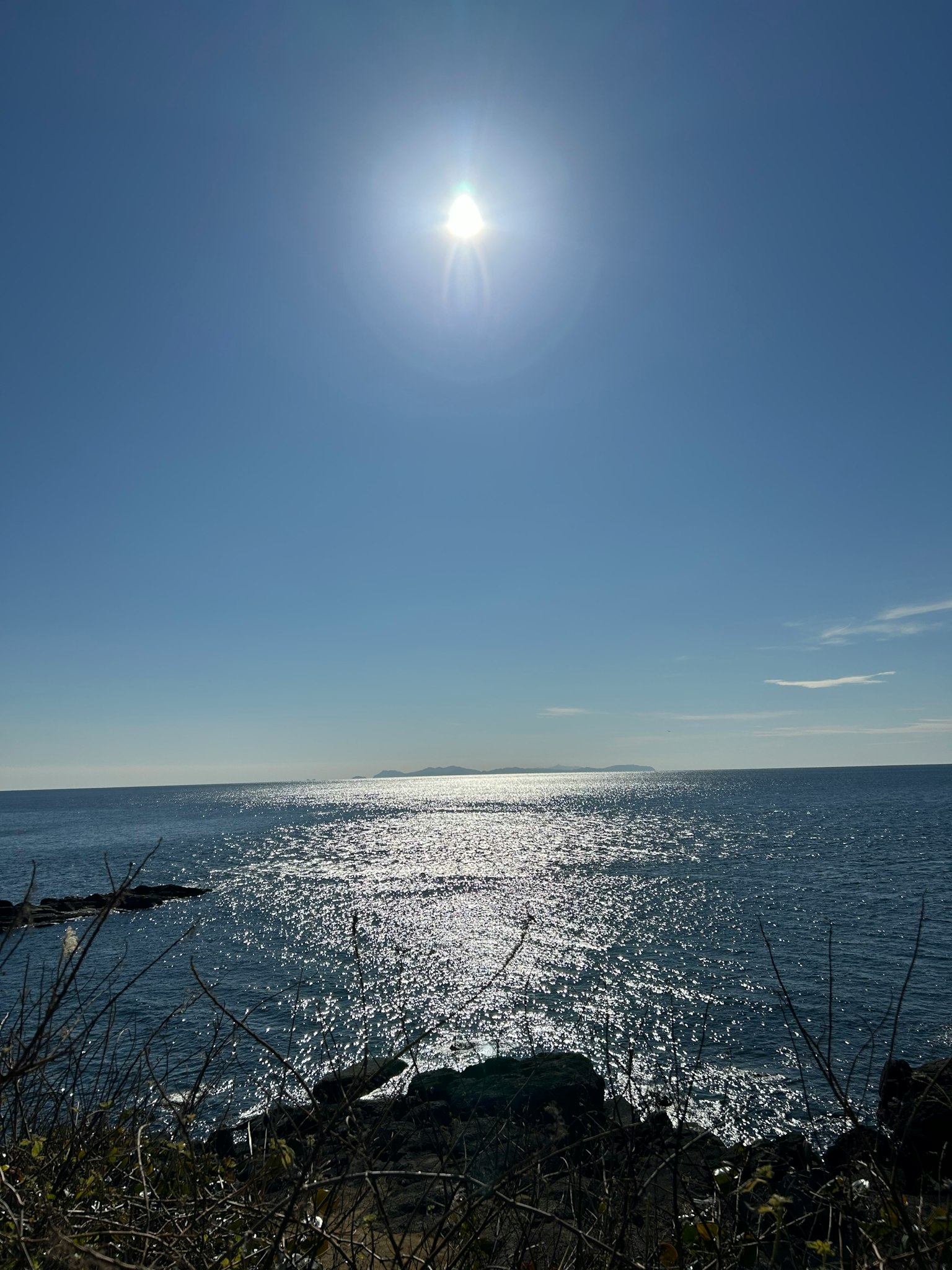 Vasto oceano blu sotto un sole luminoso con riflessi scintillanti