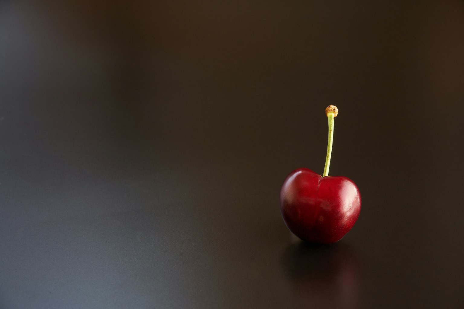 Một quả cherry đỏ trên bề mặt tối