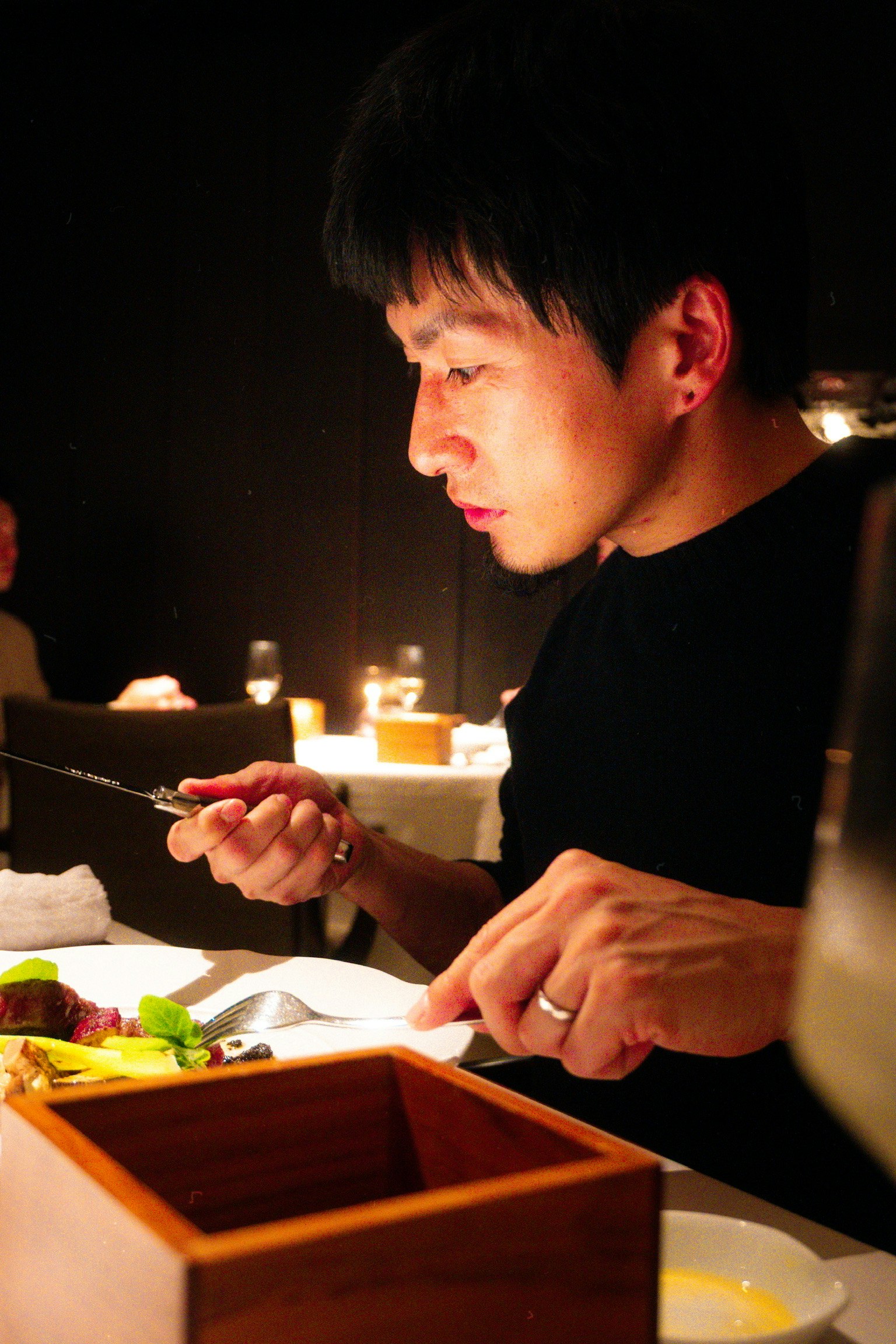 男性が料理を食べる様子 暗いレストランの雰囲気 フォークとナイフを持つ