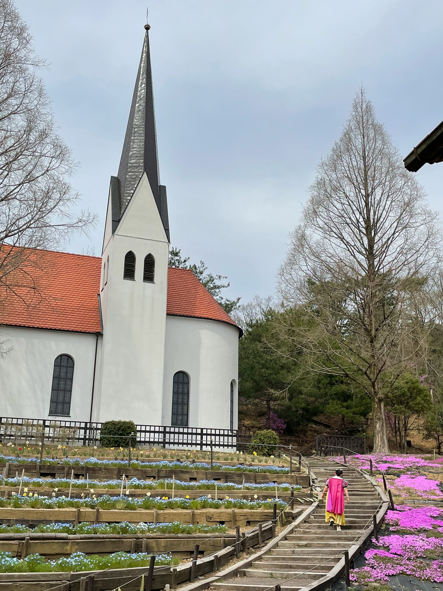 Ragazza che cammina verso una chiesa e un giardino fiorito