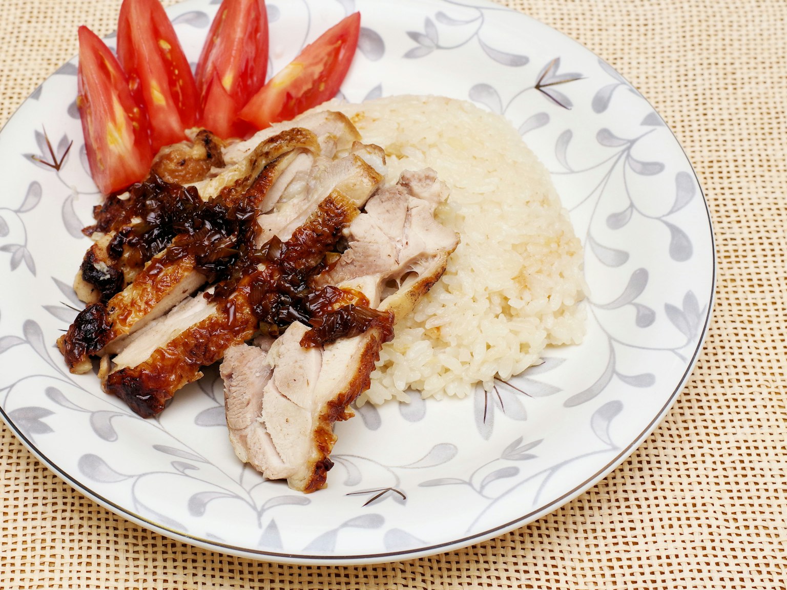 Hühnchengericht mit Reis und bunten Tomaten angerichtet