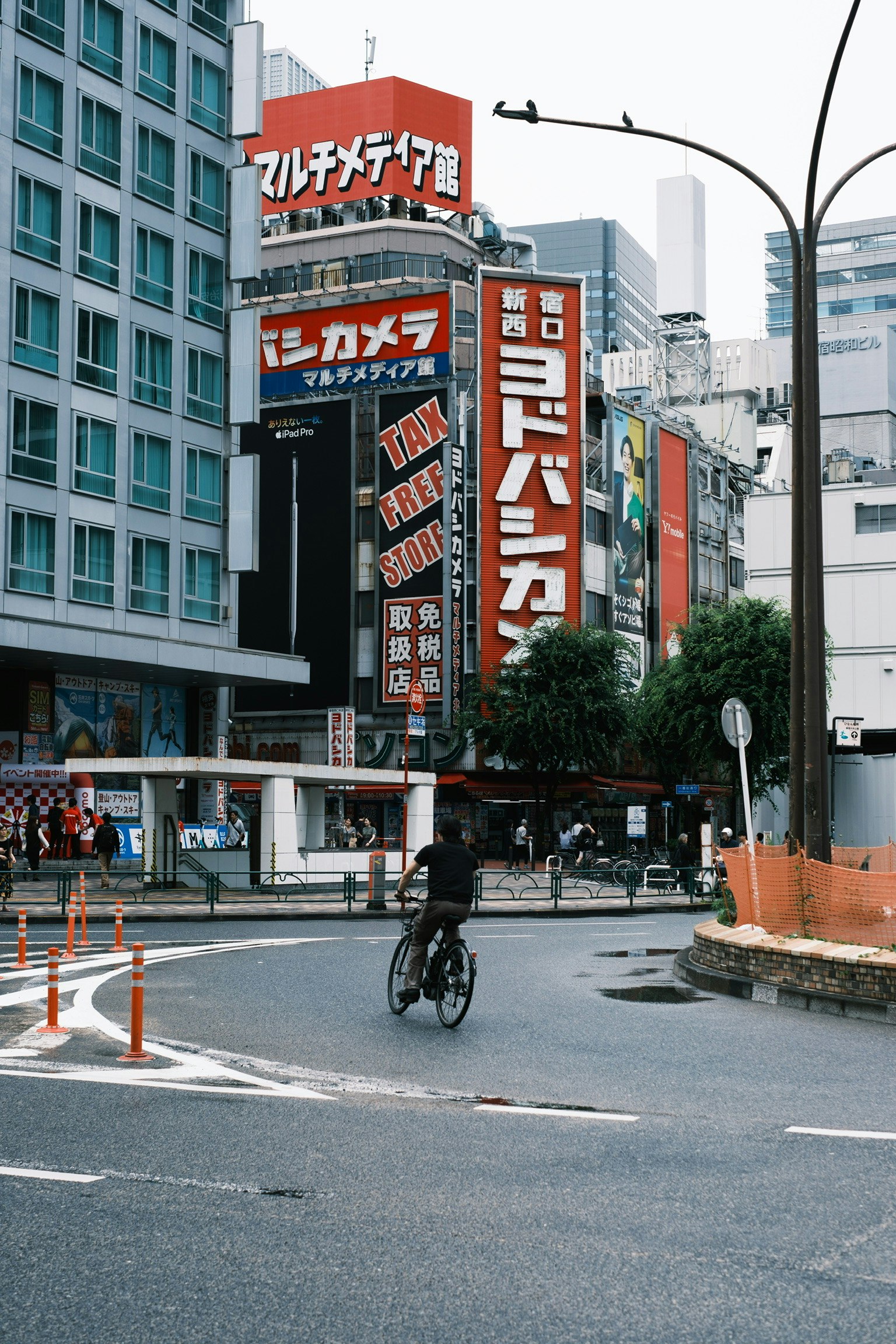 東京の街角に自転車で走る人とビルの看板が見える