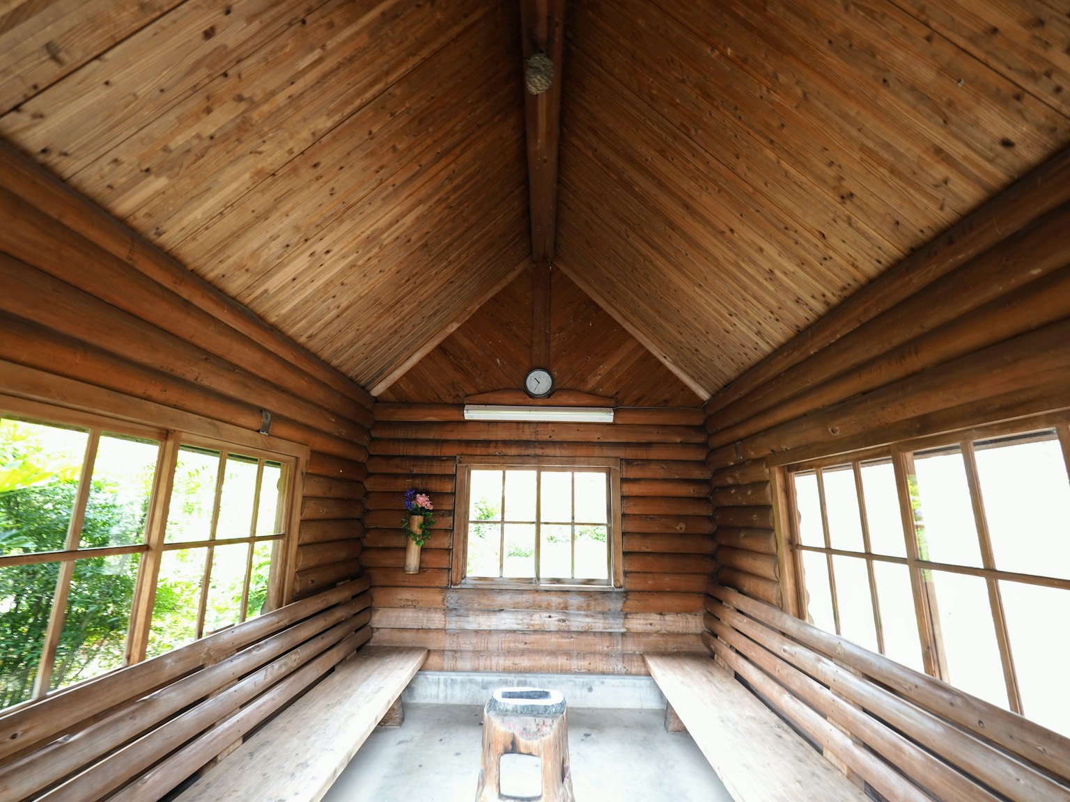 Innenraum einer Holzhütte mit hohem Decken und hellen Fenstern