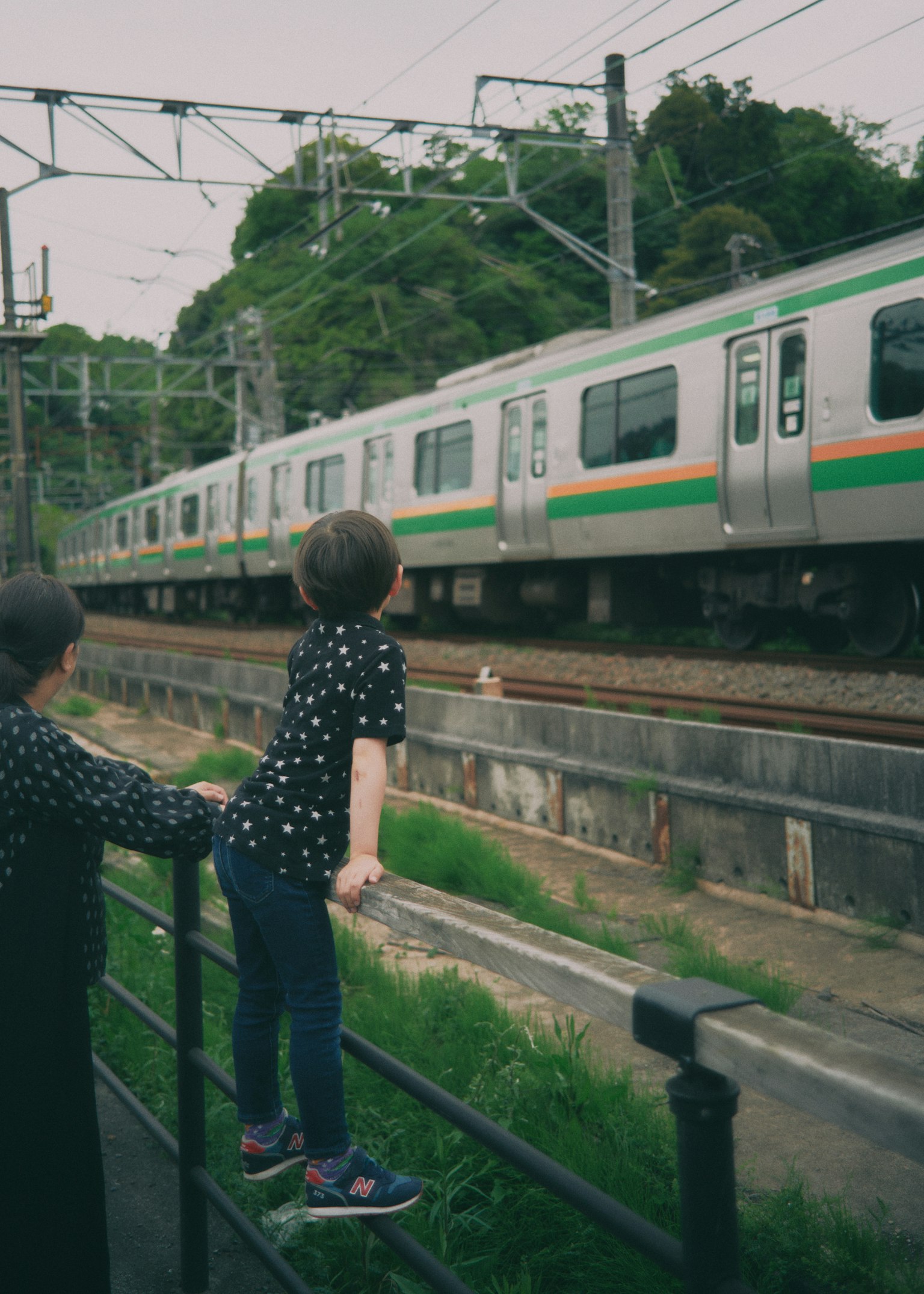 Anak-anak melihat kereta yang lewat dengan garis hijau
