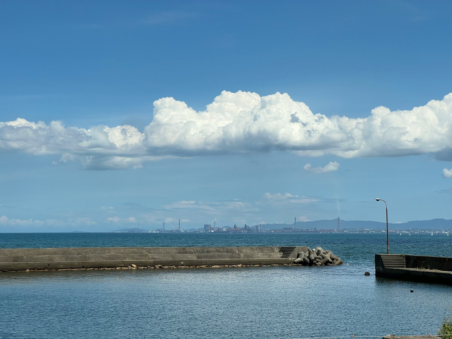平靜的海洋和藍天的風景 遠處是城市輪廓和蓬鬆的白雲