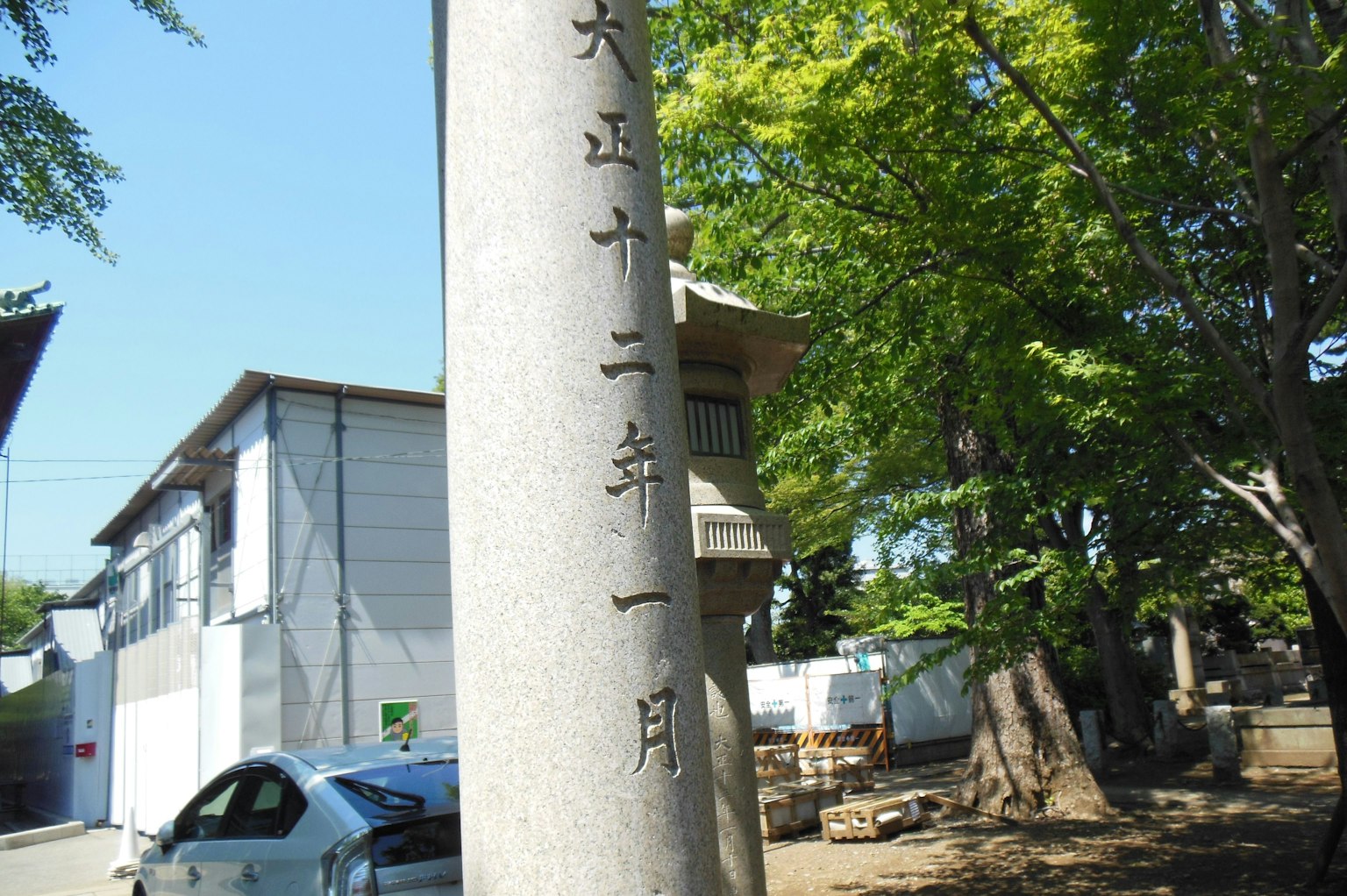 Monumen batu dengan tulisan Jepang dikelilingi pohon dan bangunan