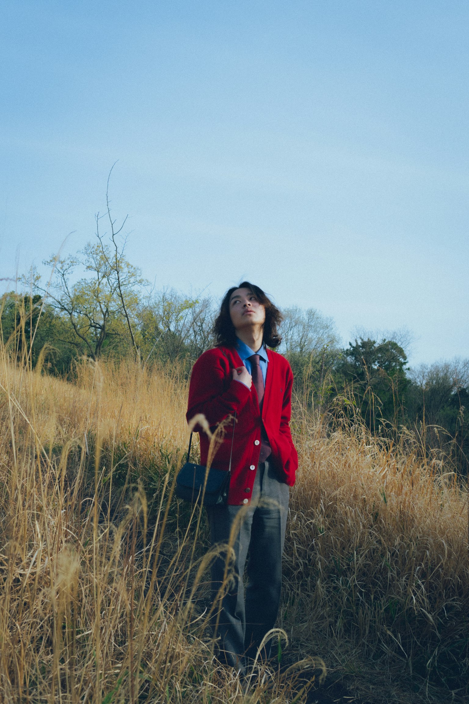 Person in a red cardigan standing in a grassy field