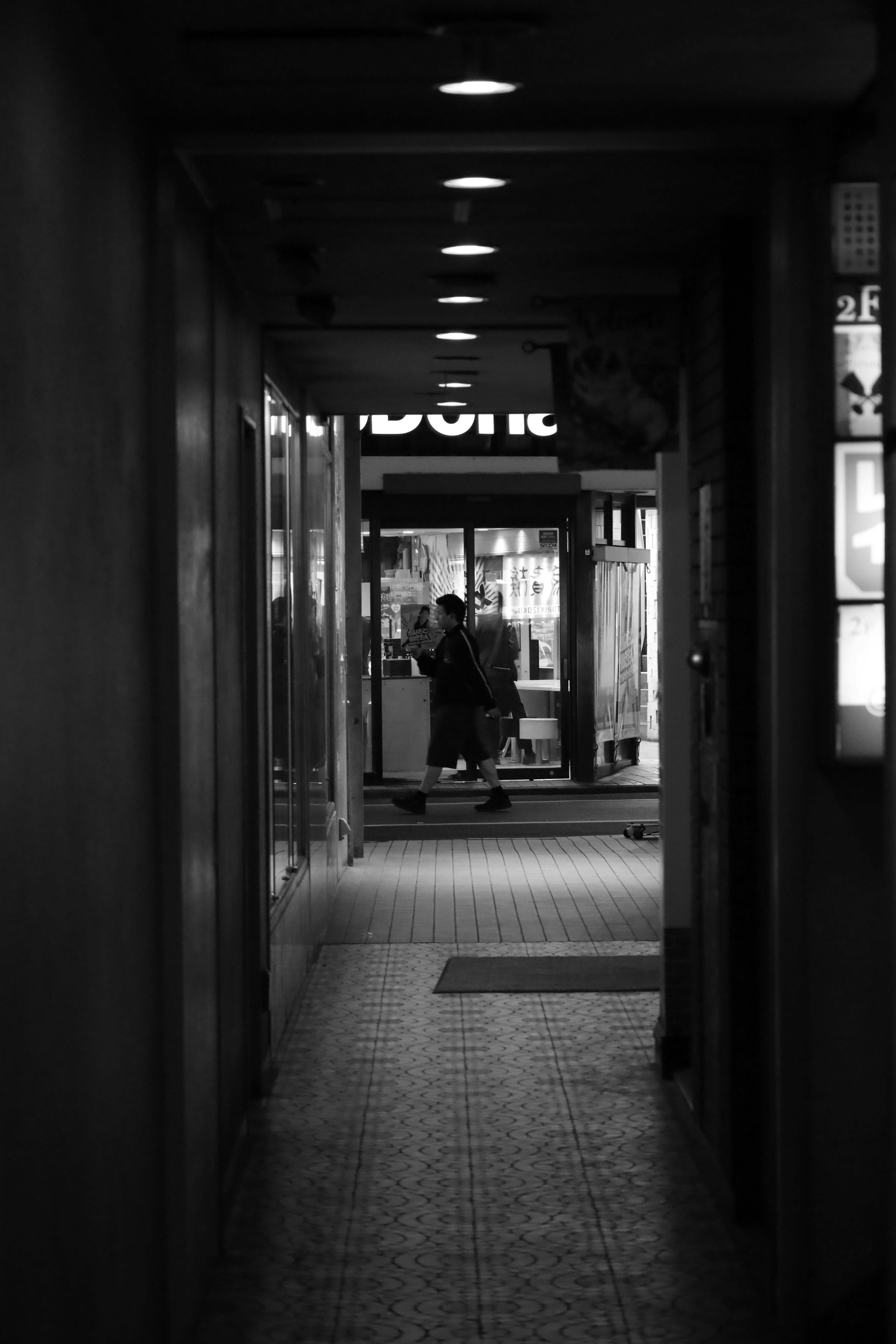 couloir d’arcade sombre avec une enseigne et une silhouette de personne au loin