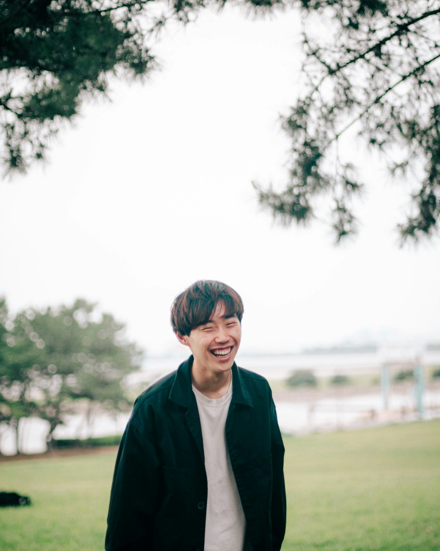 公园里微笑的男人，背景是绿色草地和树木