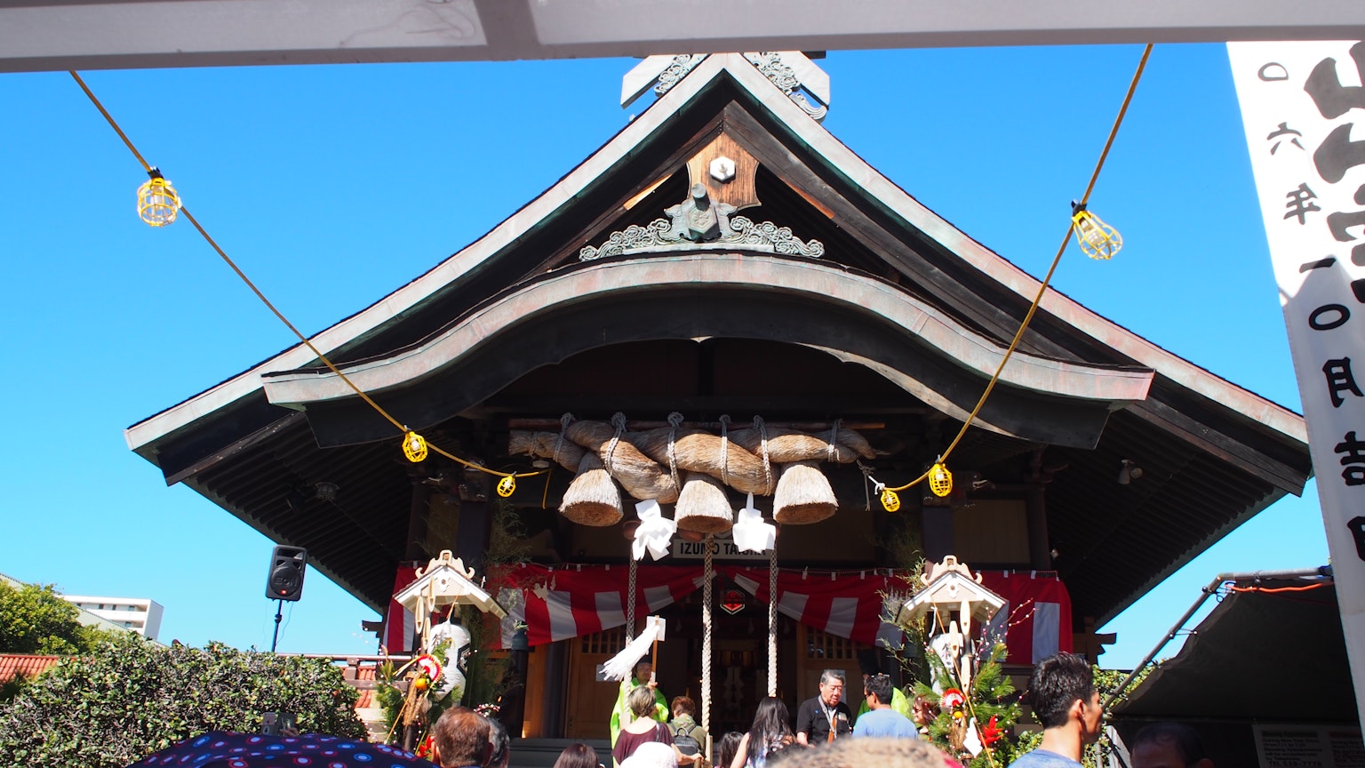 神社節日場景，藍天下有傳統建築和鈴鐺