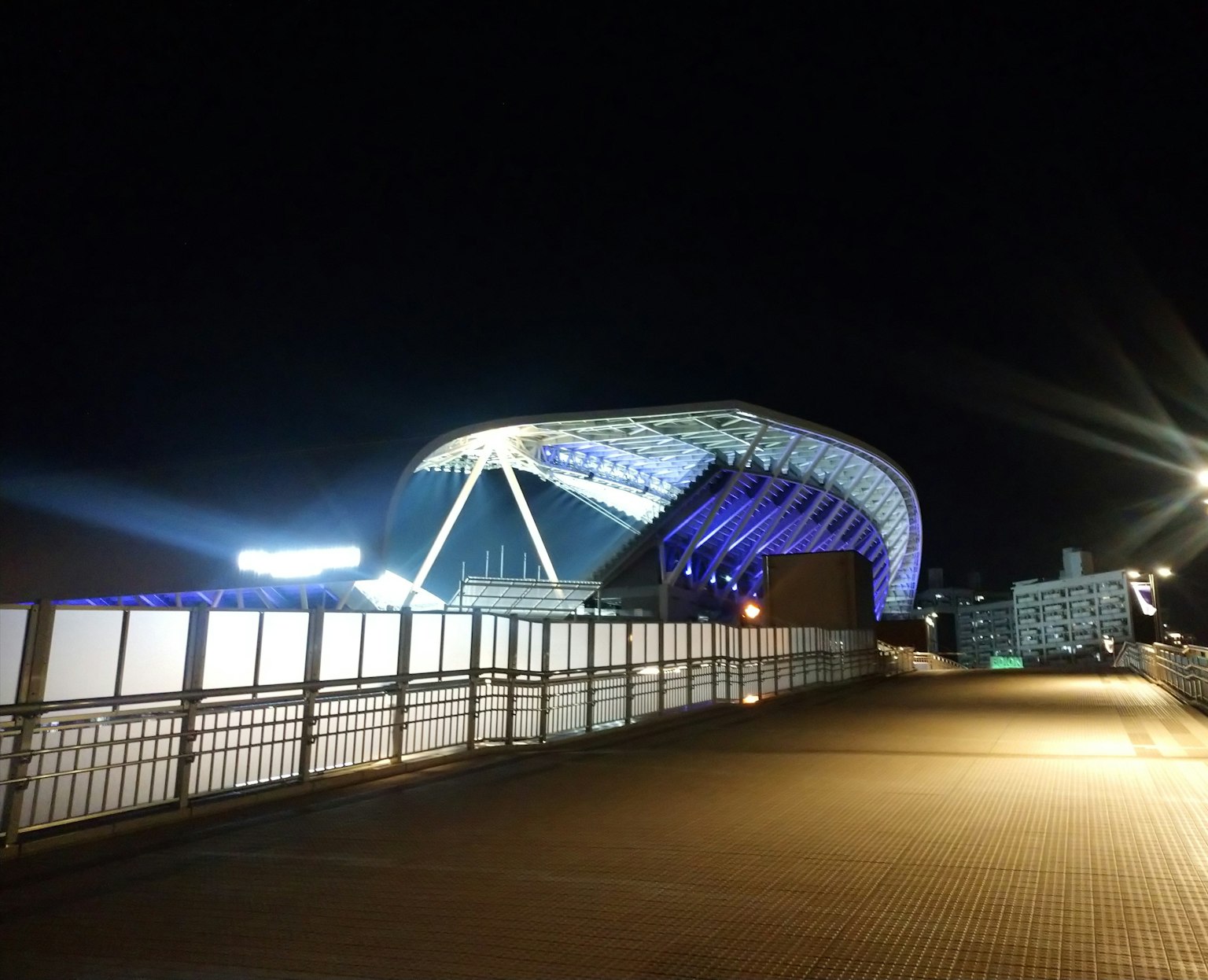 Exterior view of a stadium at night featuring bright lights and modern architecture