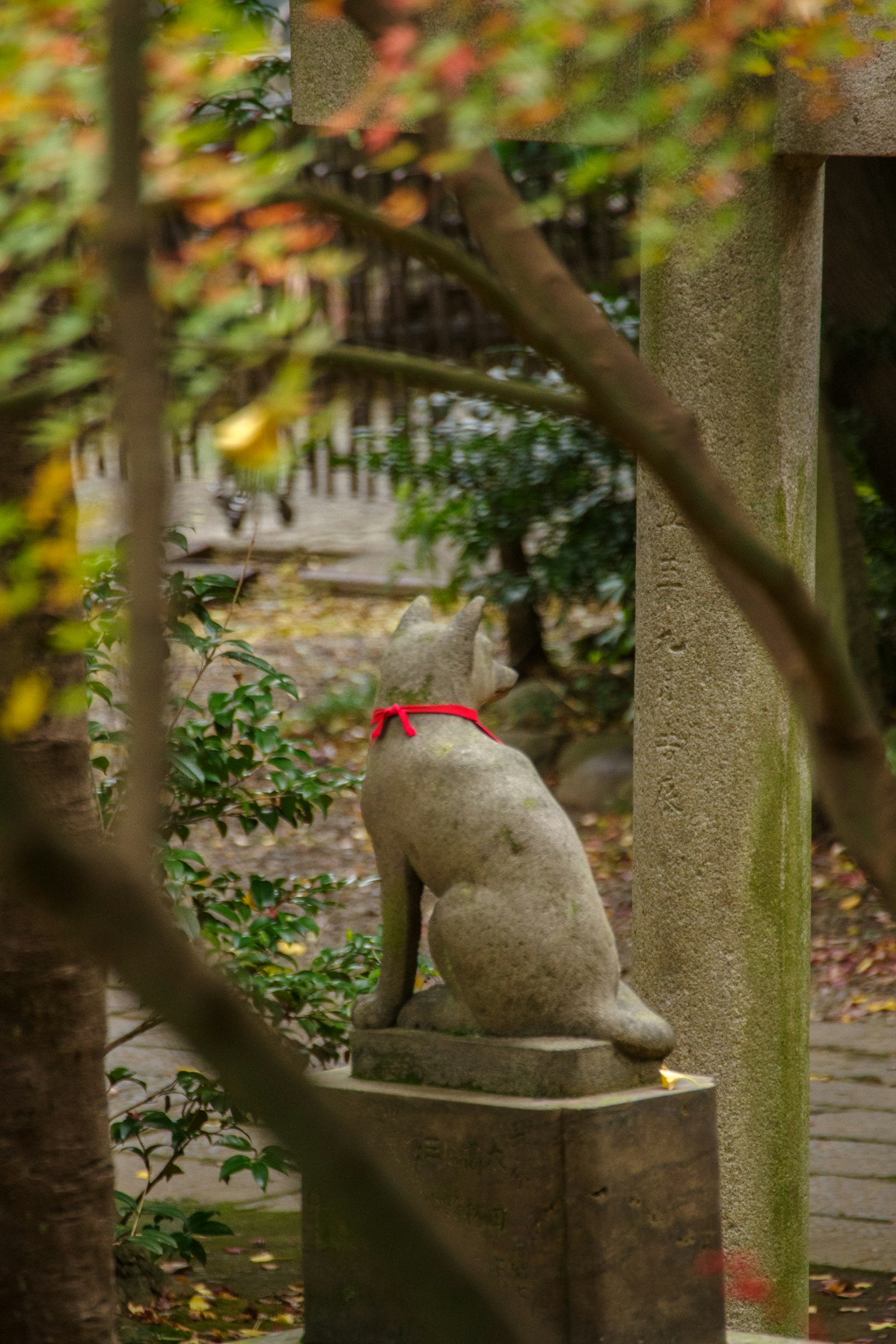 Patung rubah batu dengan pita merah di taman